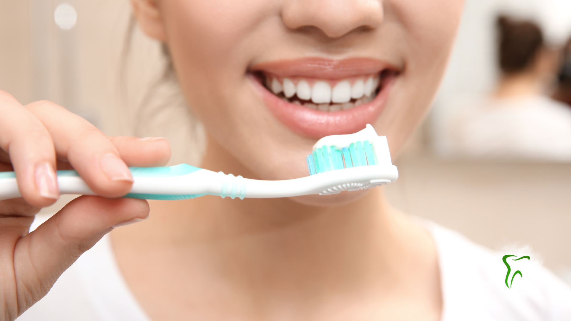 Woman smiling, holding toothbrush with toothpaste in bathroom, preparing to brush teeth.