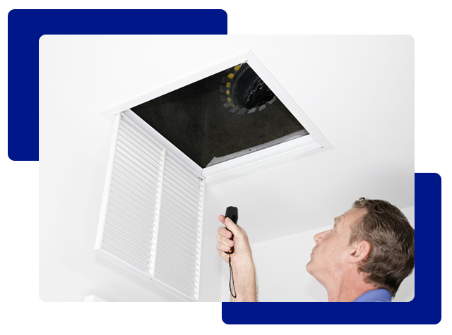 Man inspecting an air vent in a white ceiling with a flashlight.
