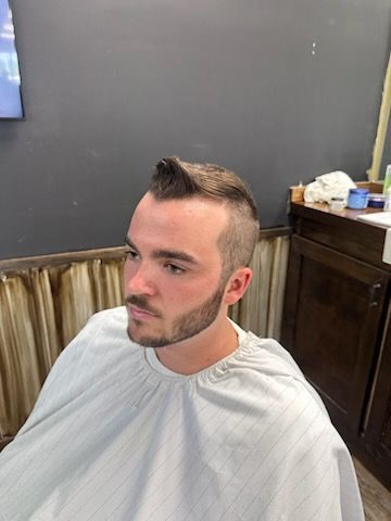 A man is getting his hair cut at a barber shop.