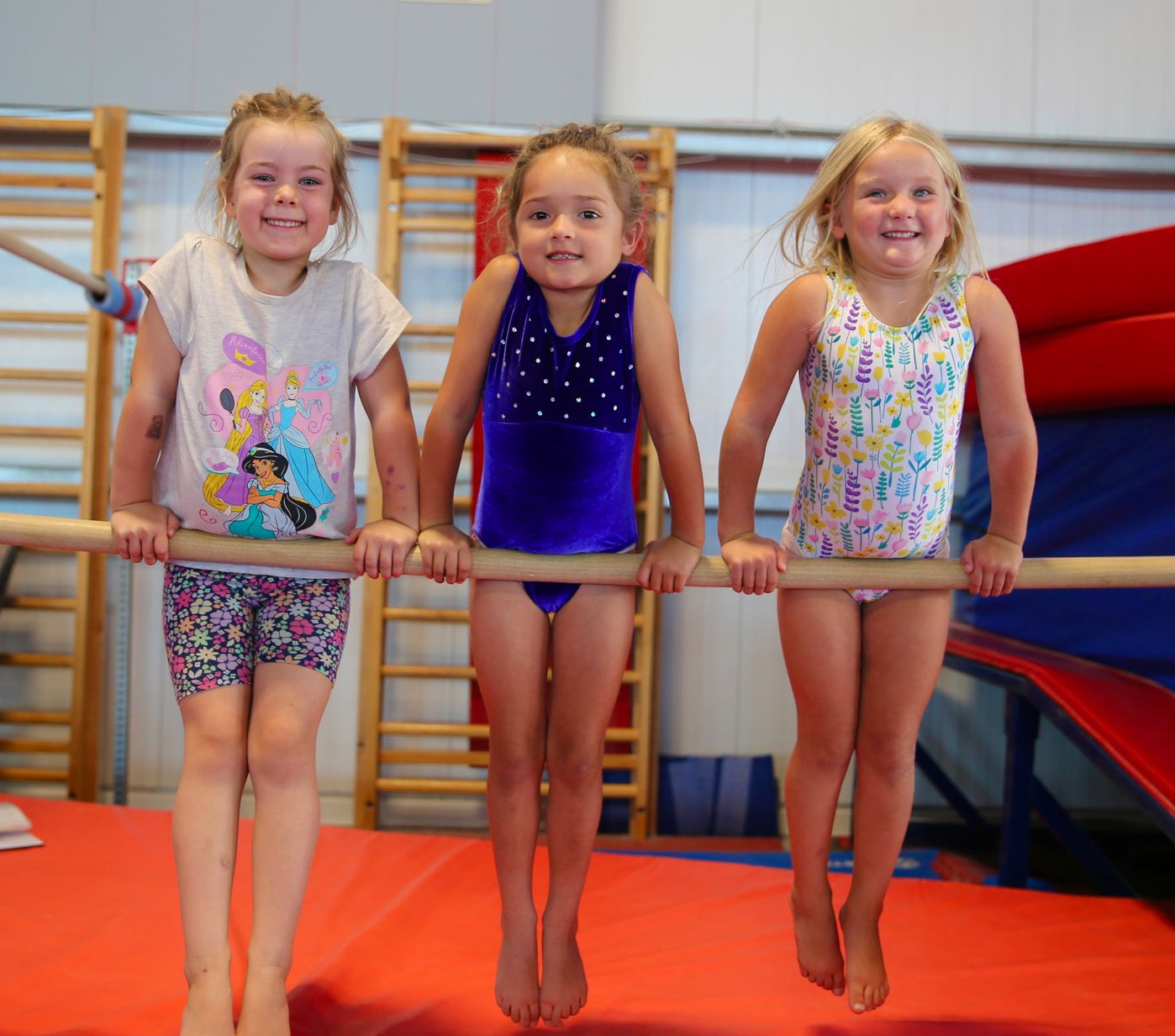 Two children smiling and holding white pom-poms in a gymnasium