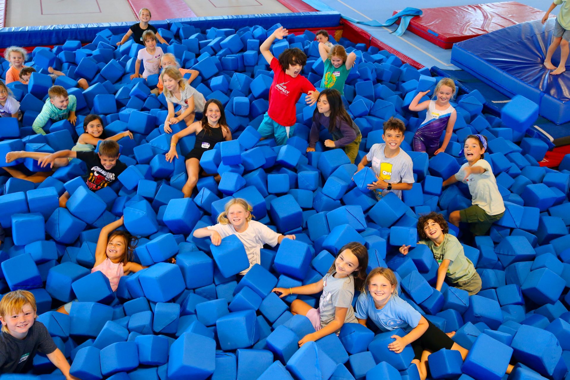 kids playing in foam pit at a gymnastics day camp