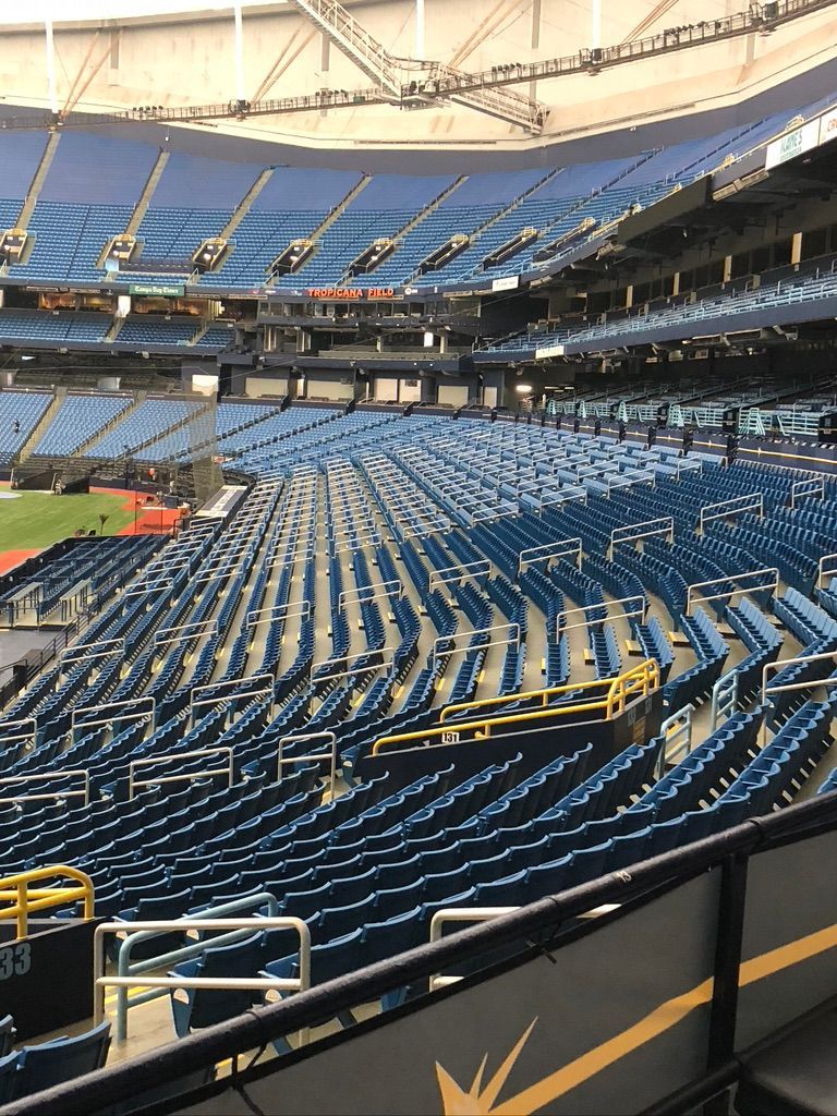 Empty baseball stadium with blue seats, under a large white roof.