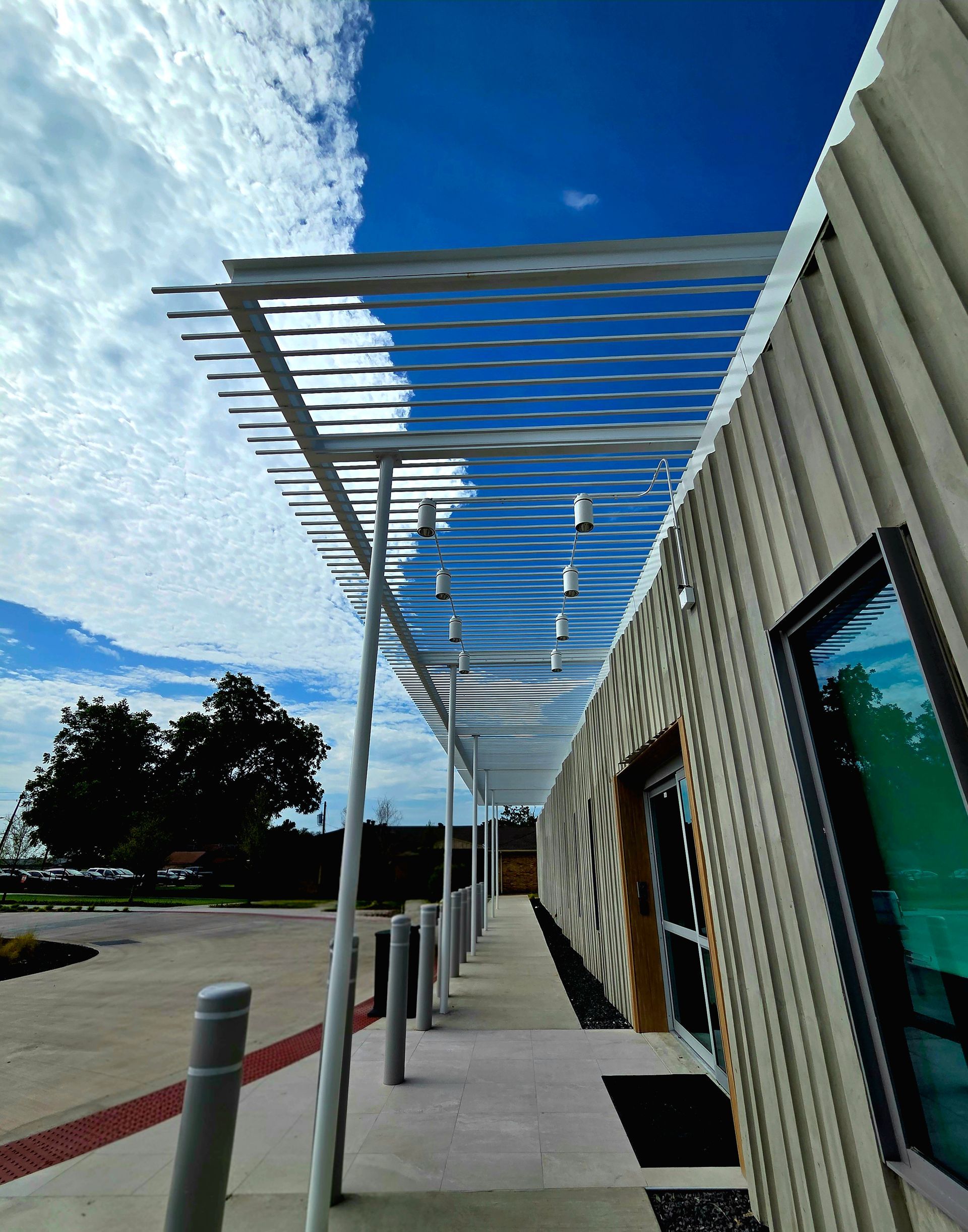 Exterior of a building with a metal awning and a walkway. Cloudy sky above.