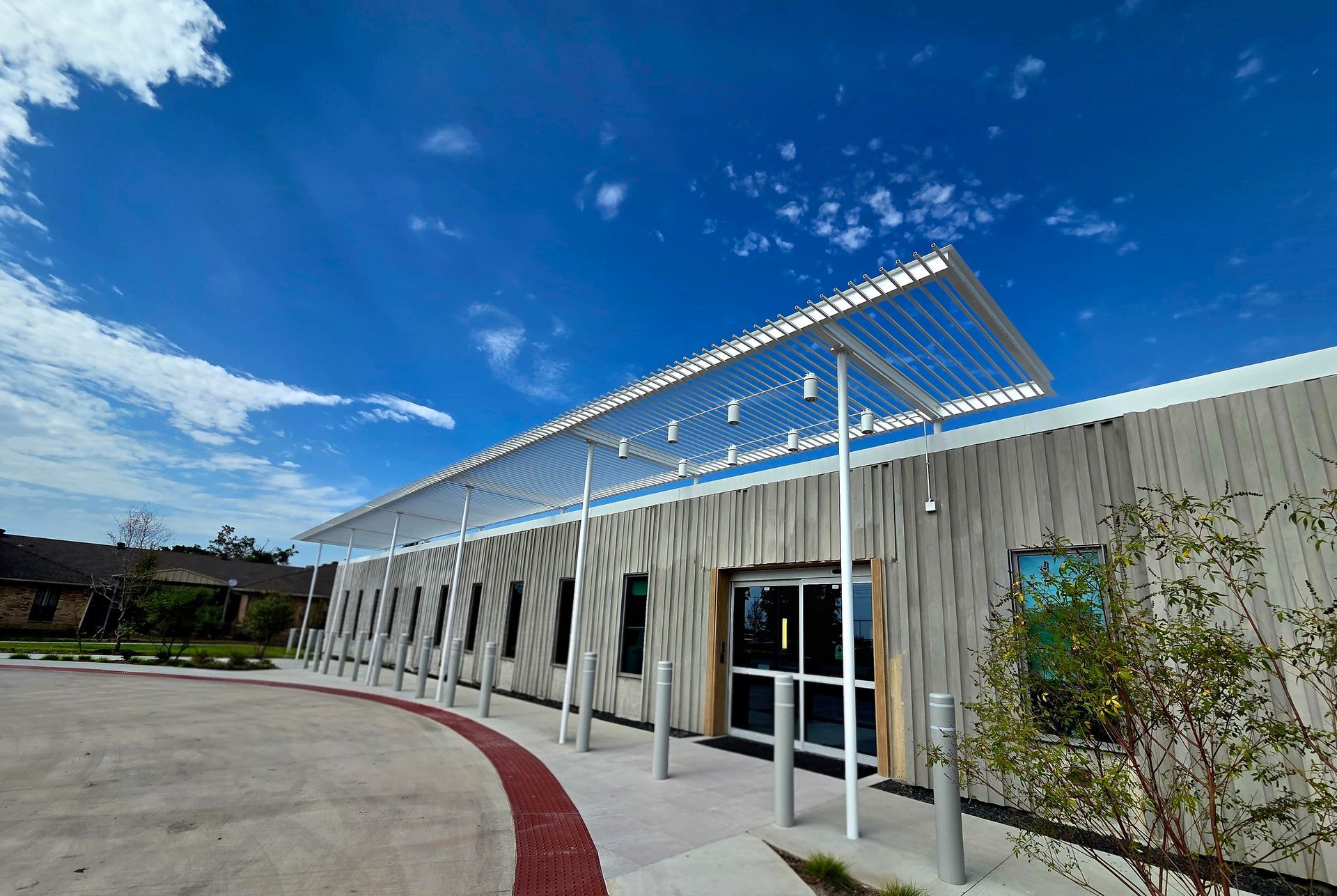 Building entrance with a metal awning, wooden siding, and a blue sky.