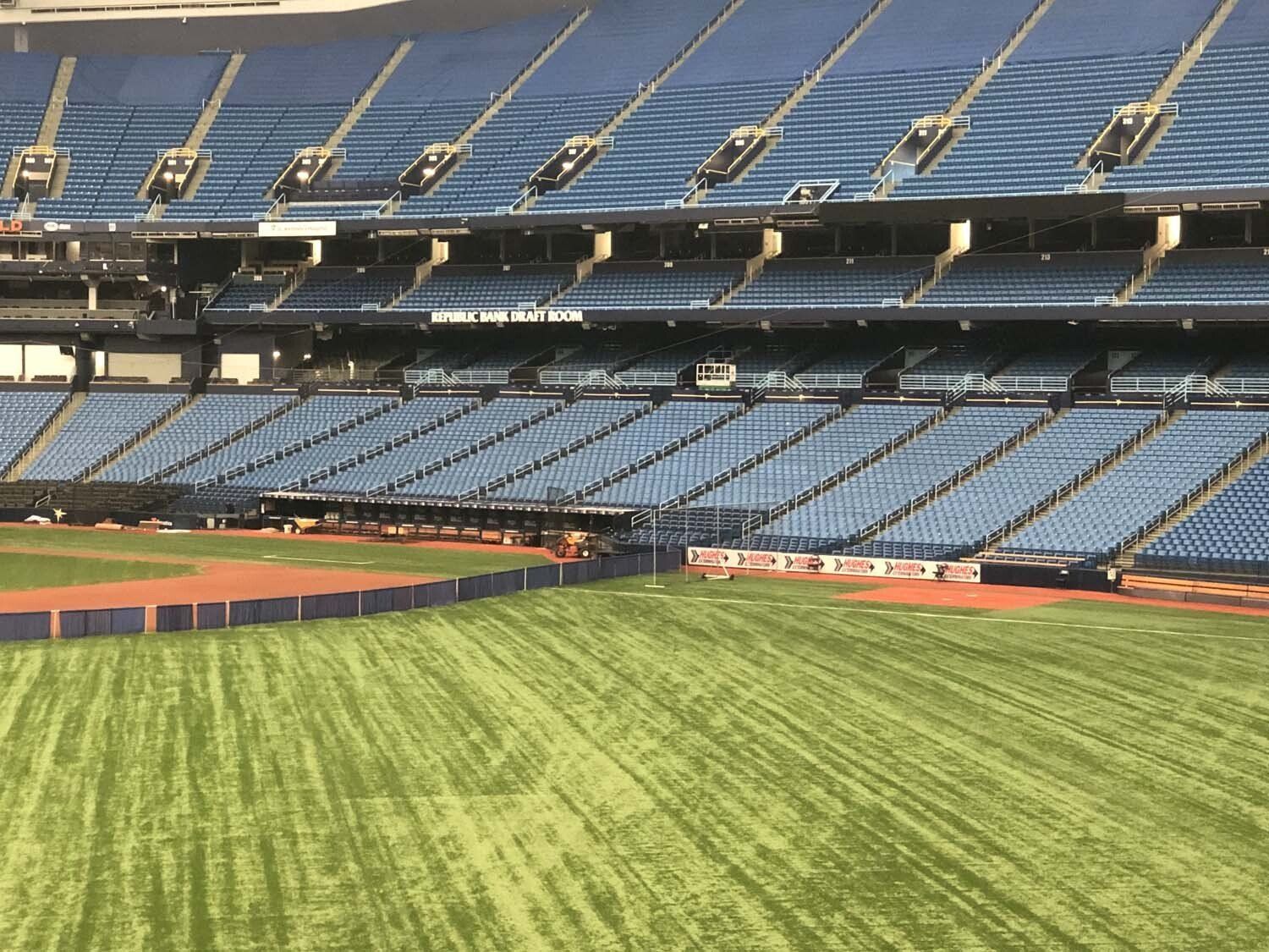 Empty baseball stadium with blue seats and green field.