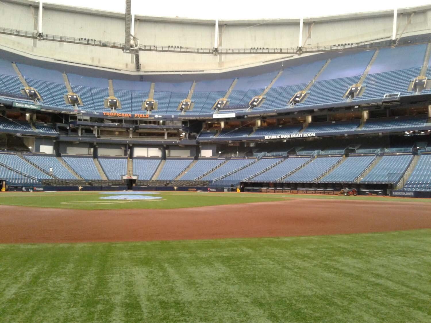 Baseball stadium interior, blue seats, green field, brown infield. 