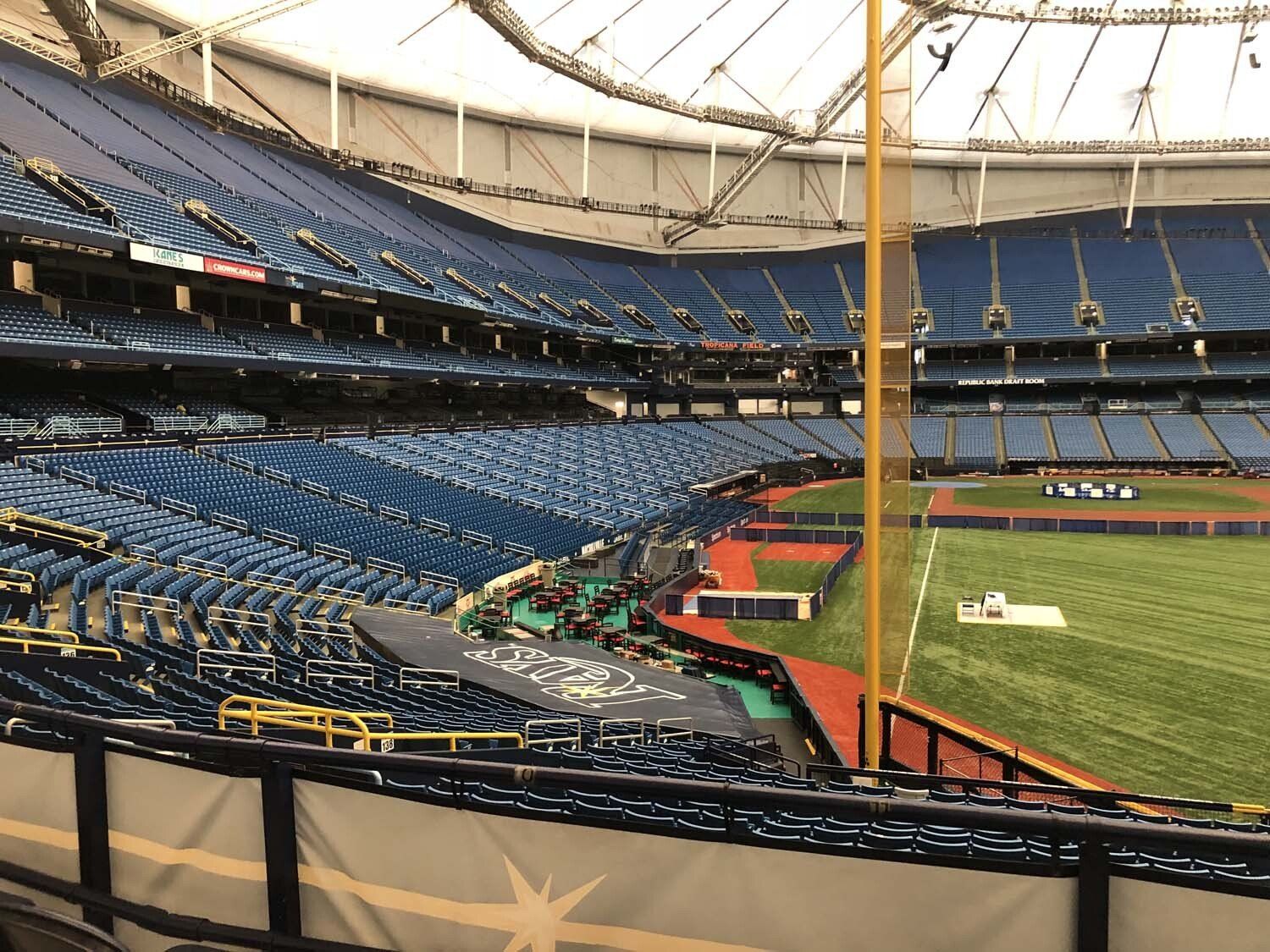 Empty baseball stadium with blue seats, green field, and retractable roof.