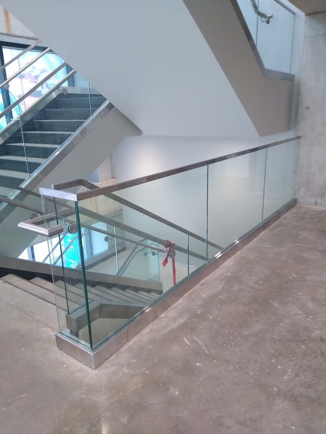 Glass and steel staircase with frosted glass railings in a building.
