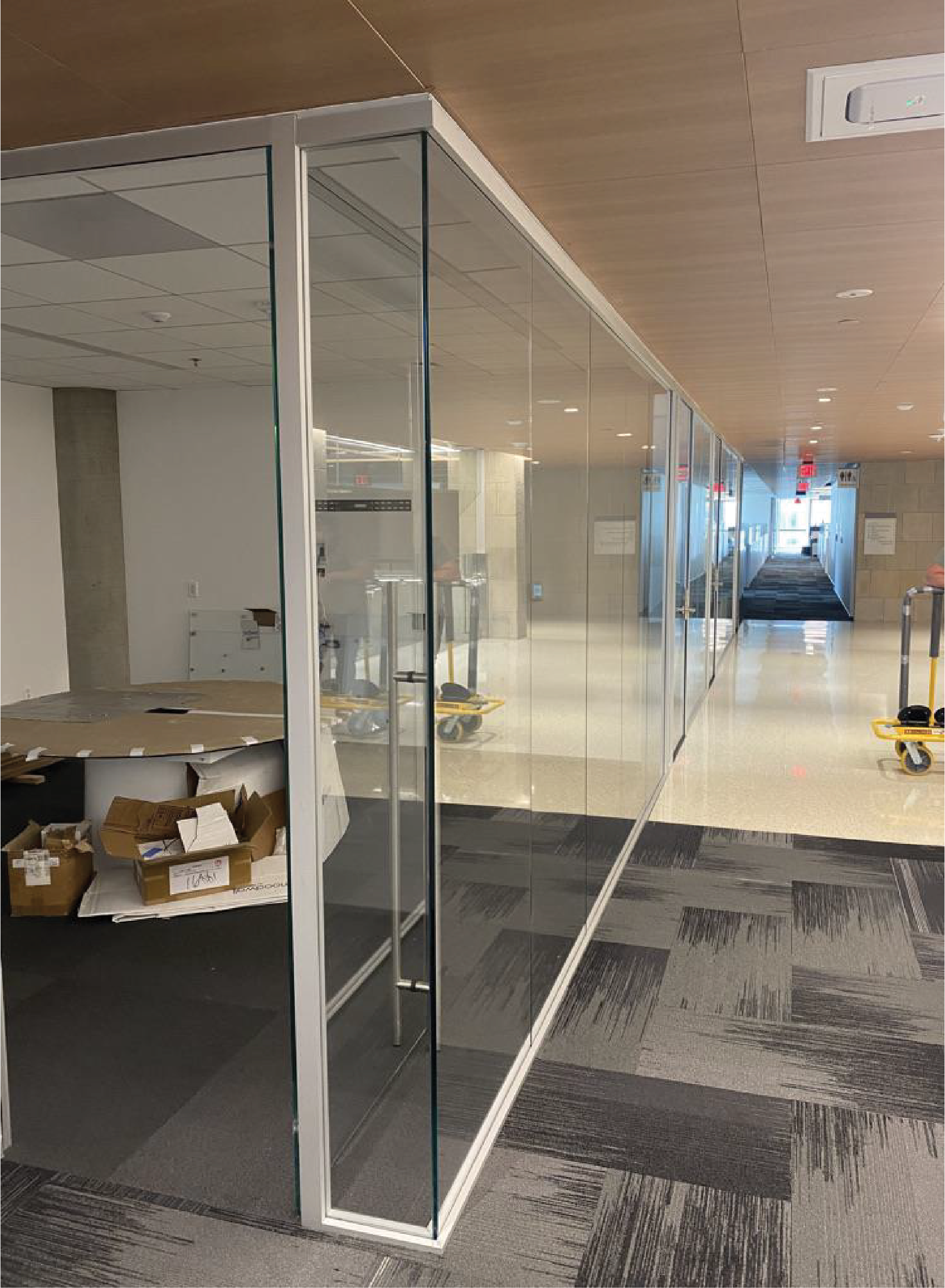 Glass office wall with aluminum frame in a hallway.