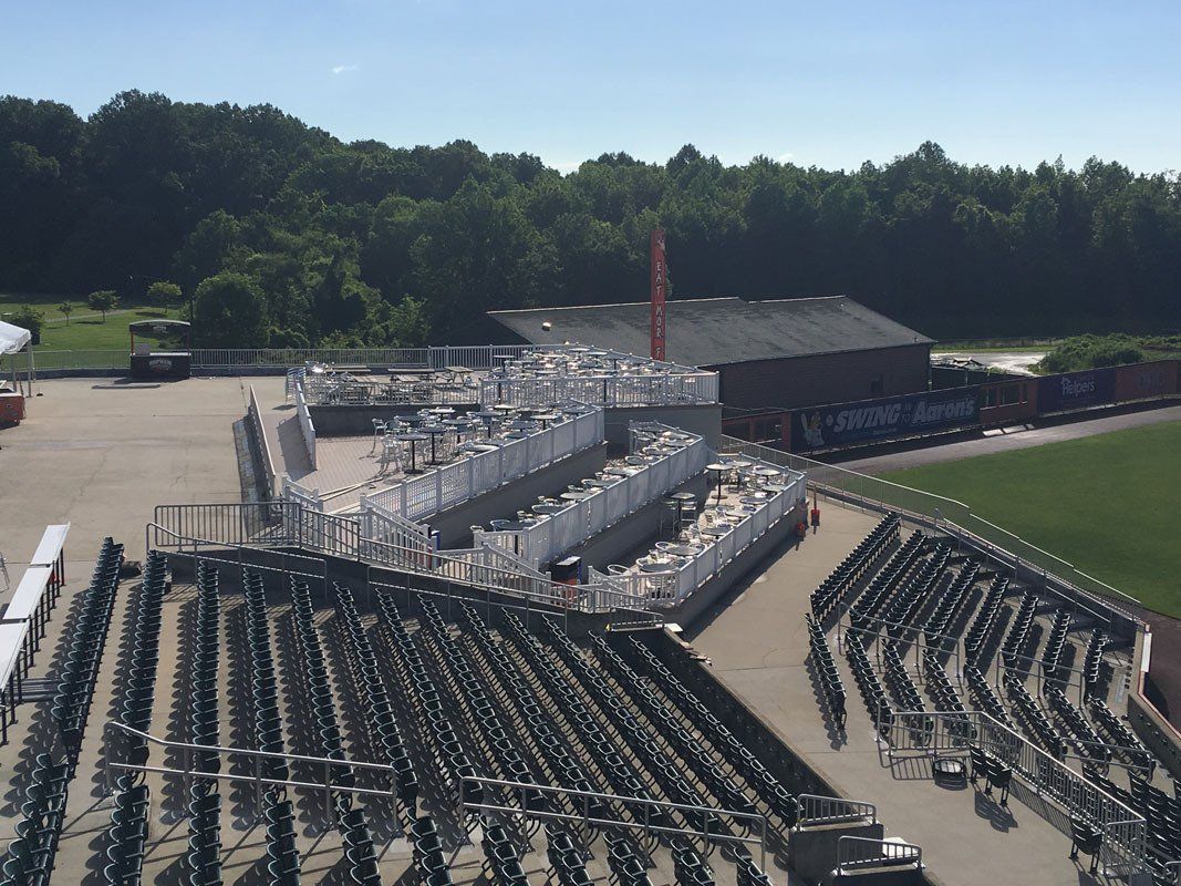 Construction site with stadium seating, trees, and blue sky.
