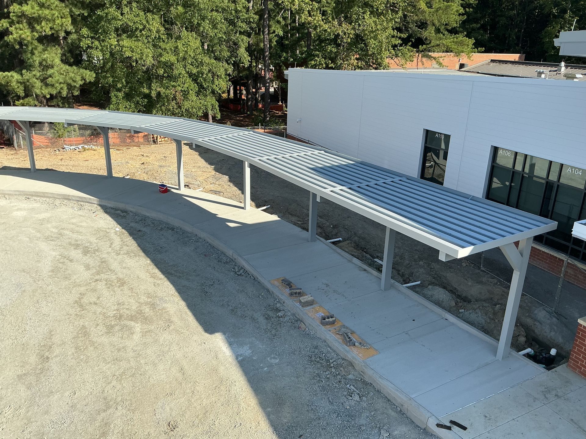 Exterior of a building with a metal awning and a walkway. Cloudy sky above.