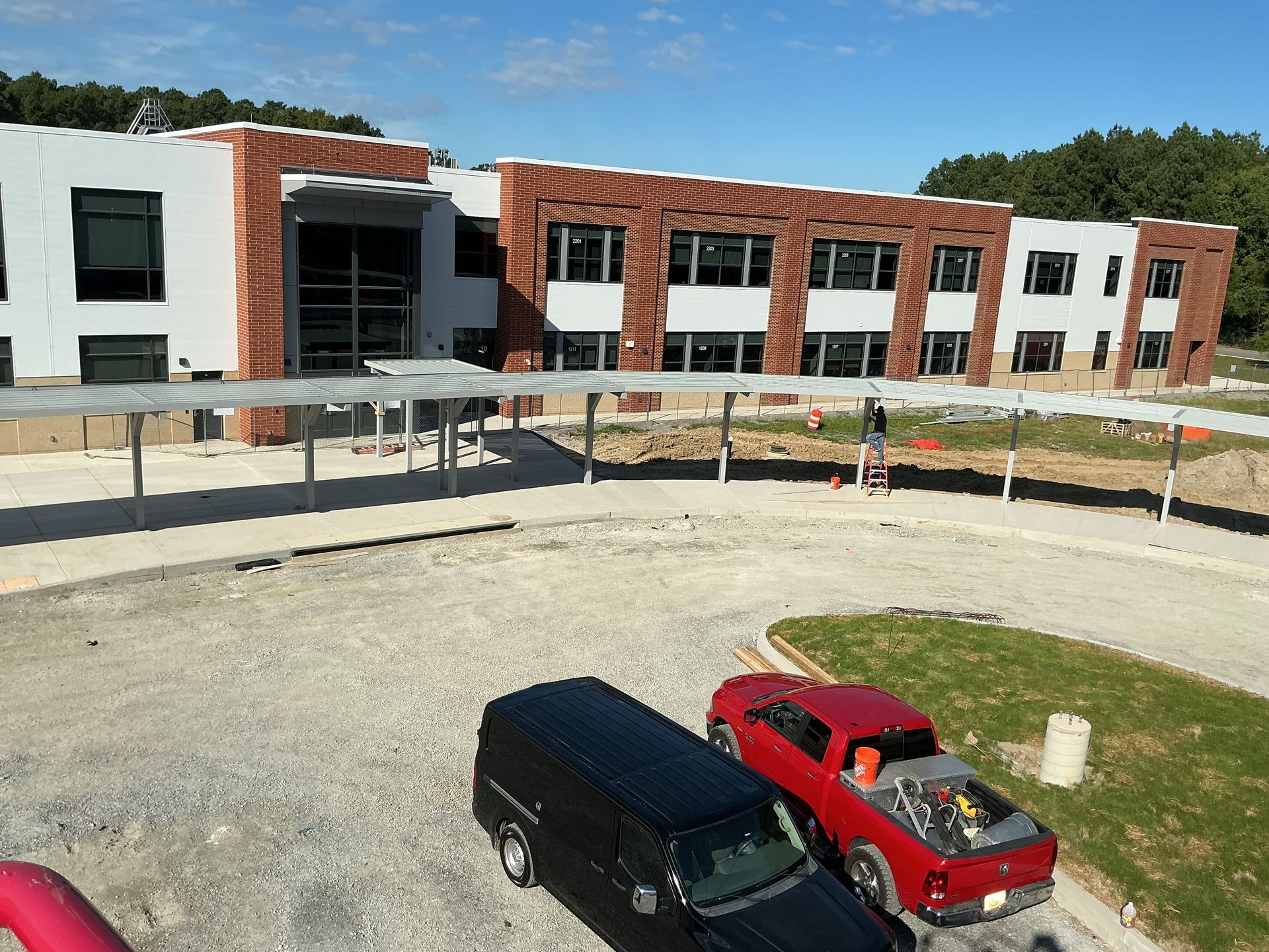 Exterior of a building with a metal awning and a walkway. Cloudy sky above.