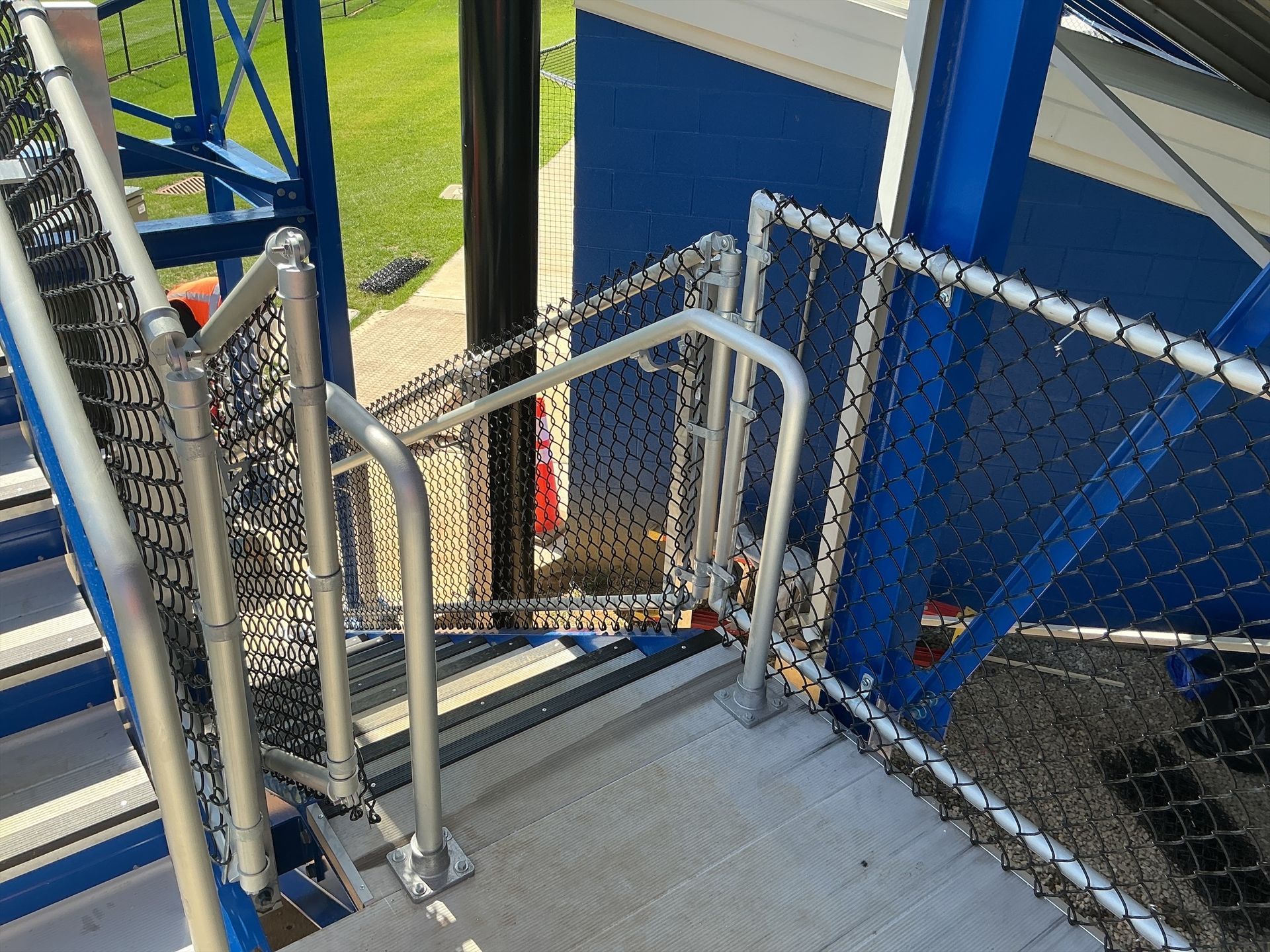 Staircase with safety railing and netting, painted blue and silver, outdoors.
