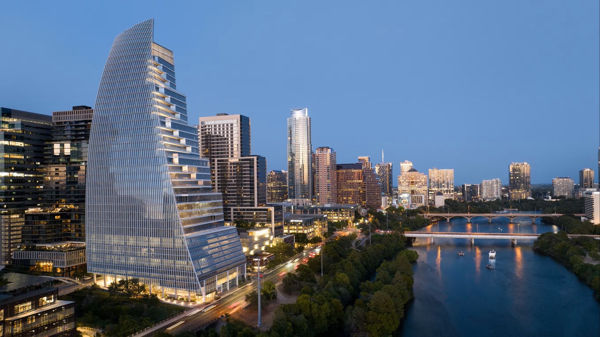 Skyscraper with curved glass facade, overlooking a city skyline at dusk, near a river with bridge.