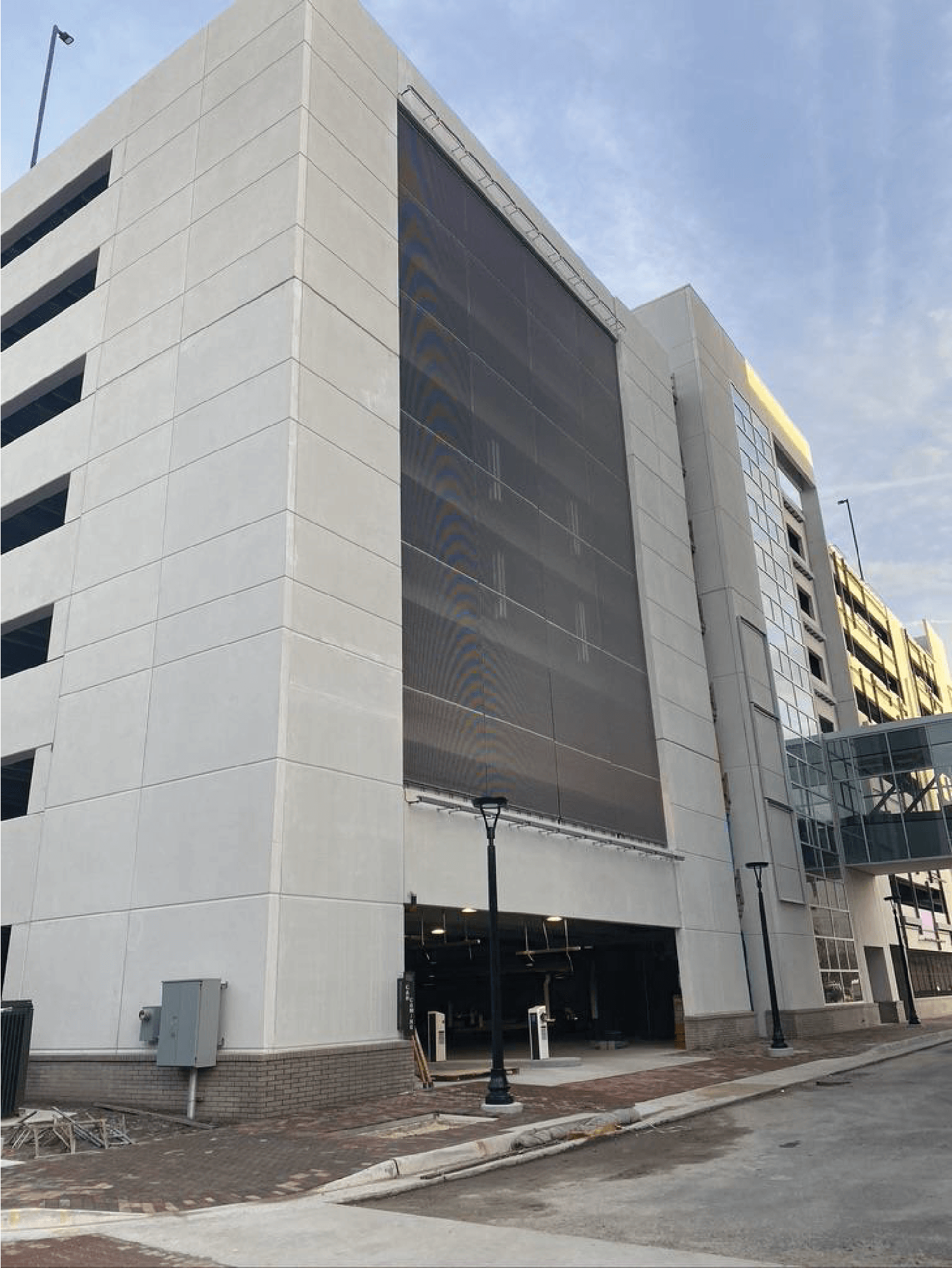 Parking garage with white exterior, drive-in entrance, and a pedestrian bridge.