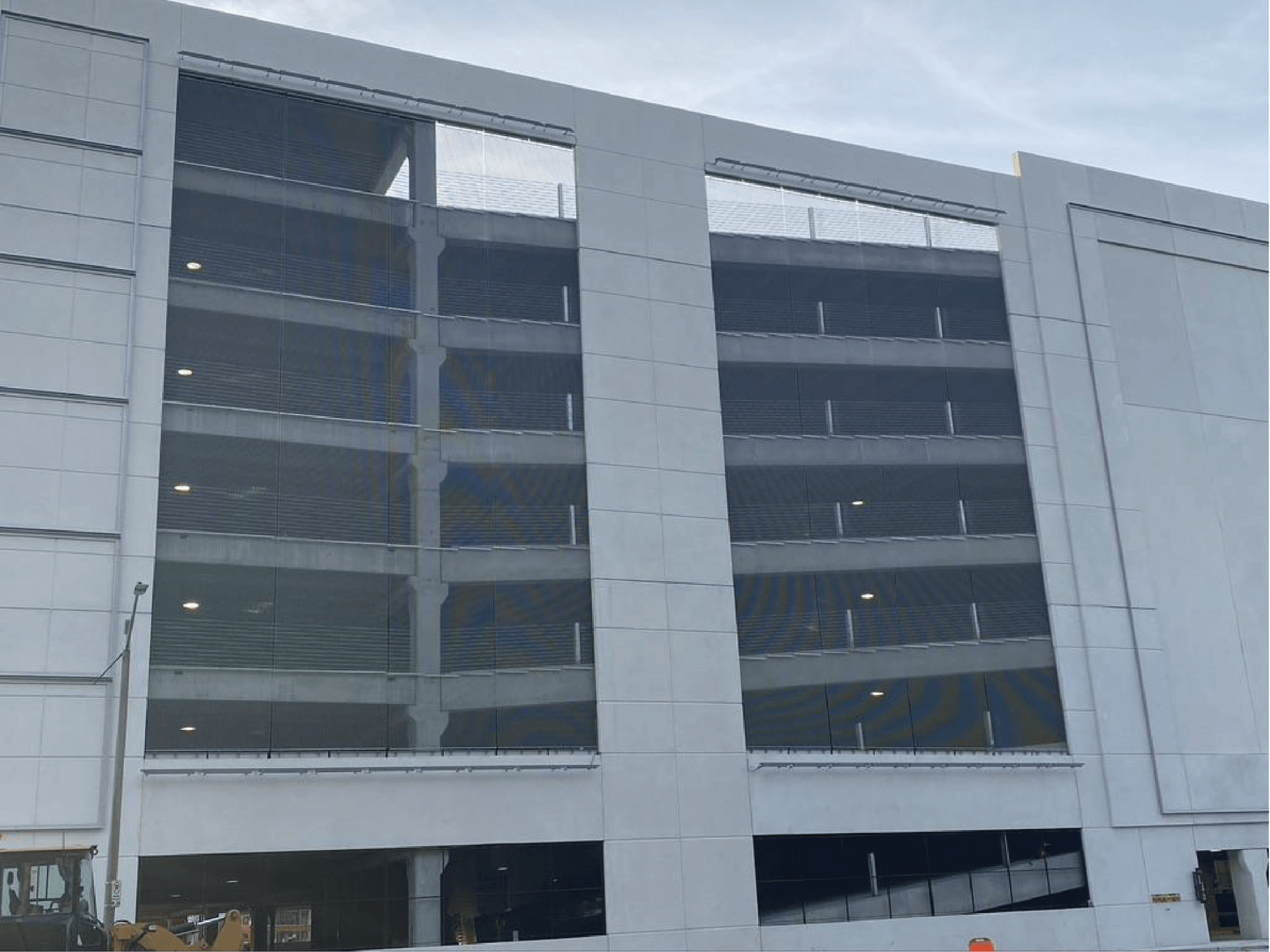 Exterior view of a multi-story parking garage; gray concrete and metal mesh construction.