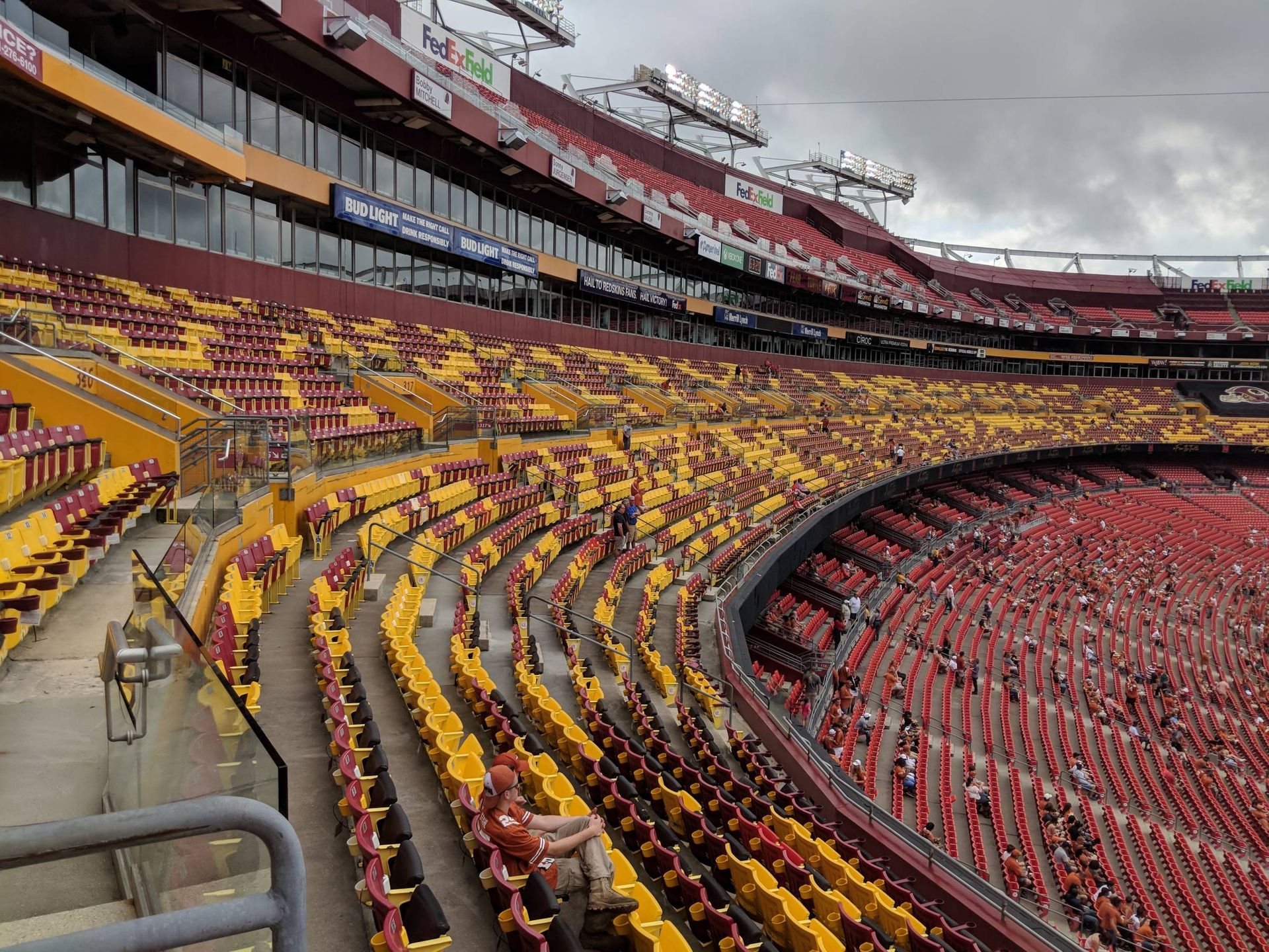 Empty stadium seats, red and gold colors. Overcast sky.