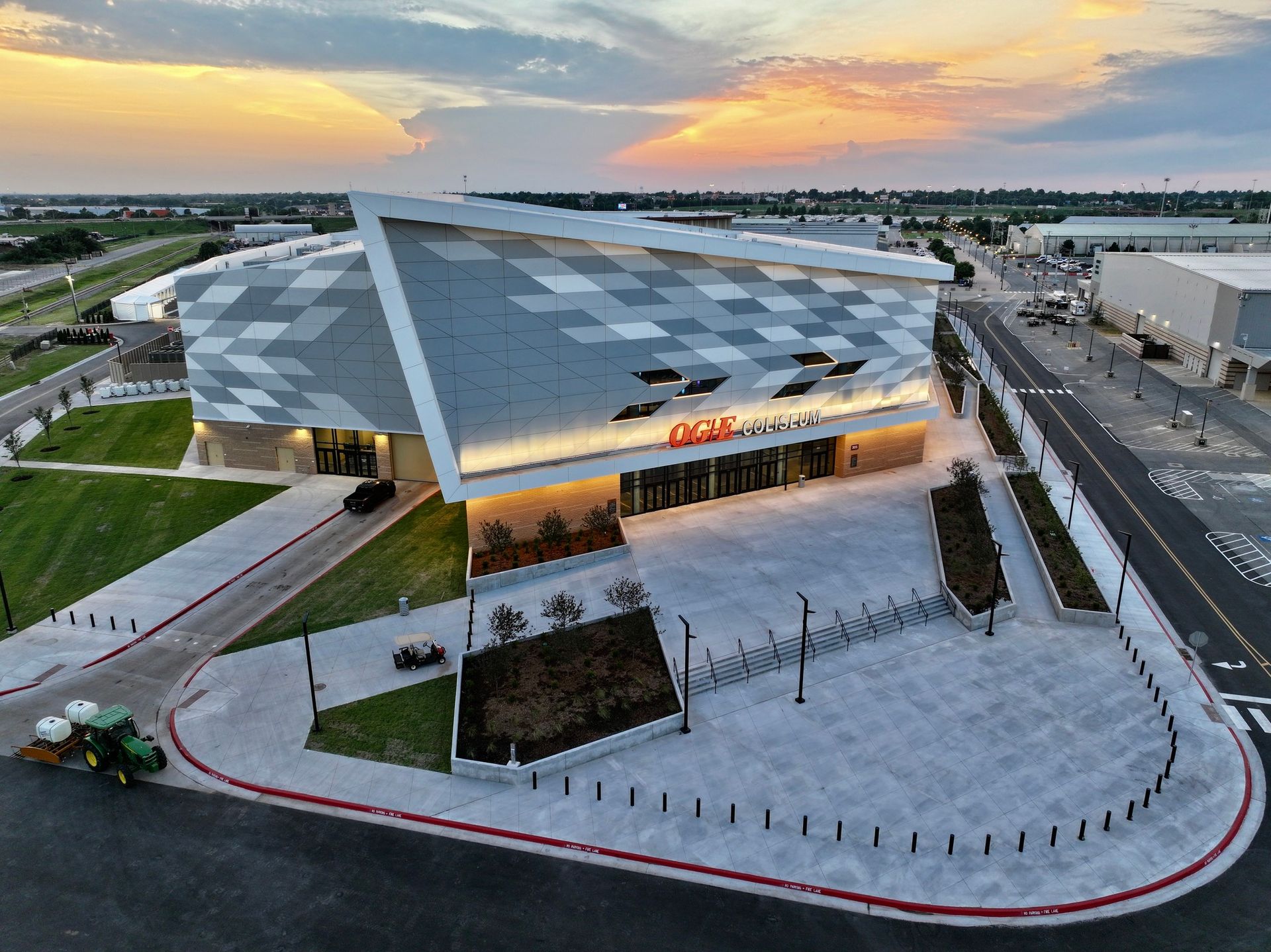 Modern arena exterior with angled roof, at sunset.