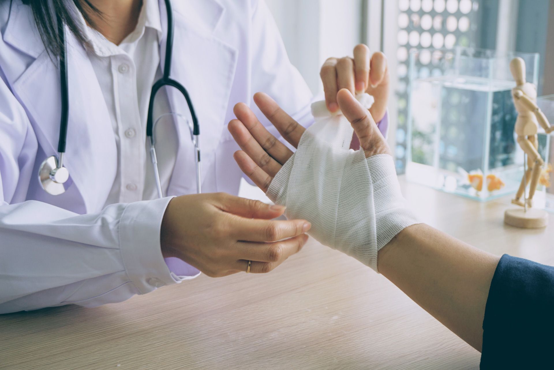 Doctor wrapping a patient's injured hand with a bandage in a doctor's office.