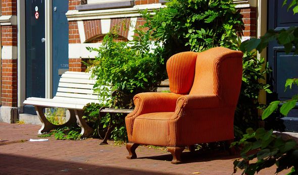 A split-screen view: a pile of trash and furniture on a lawn, and a couple standing in front of the same tidy house.