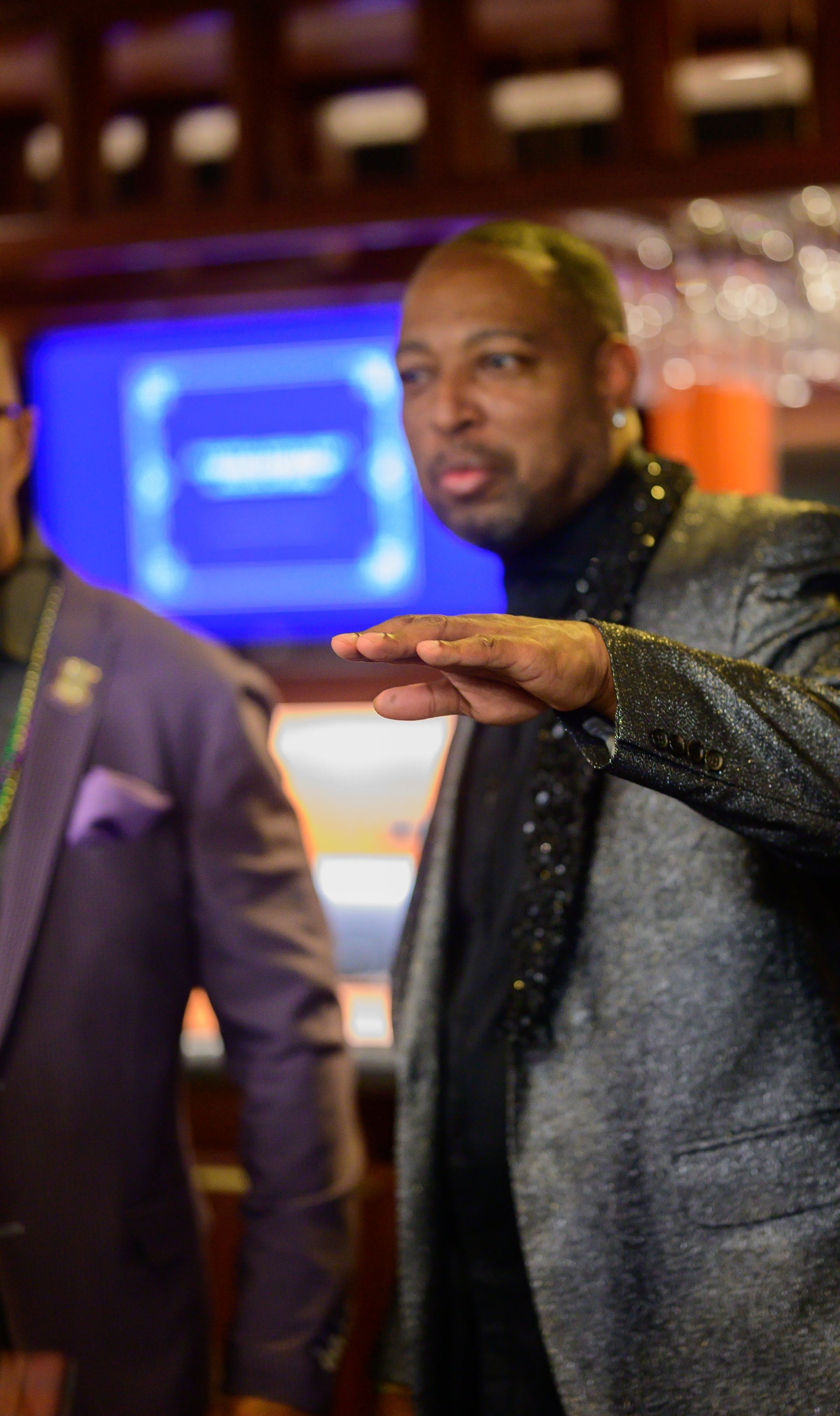 A man in a suit is standing next to another man in a purple suit.