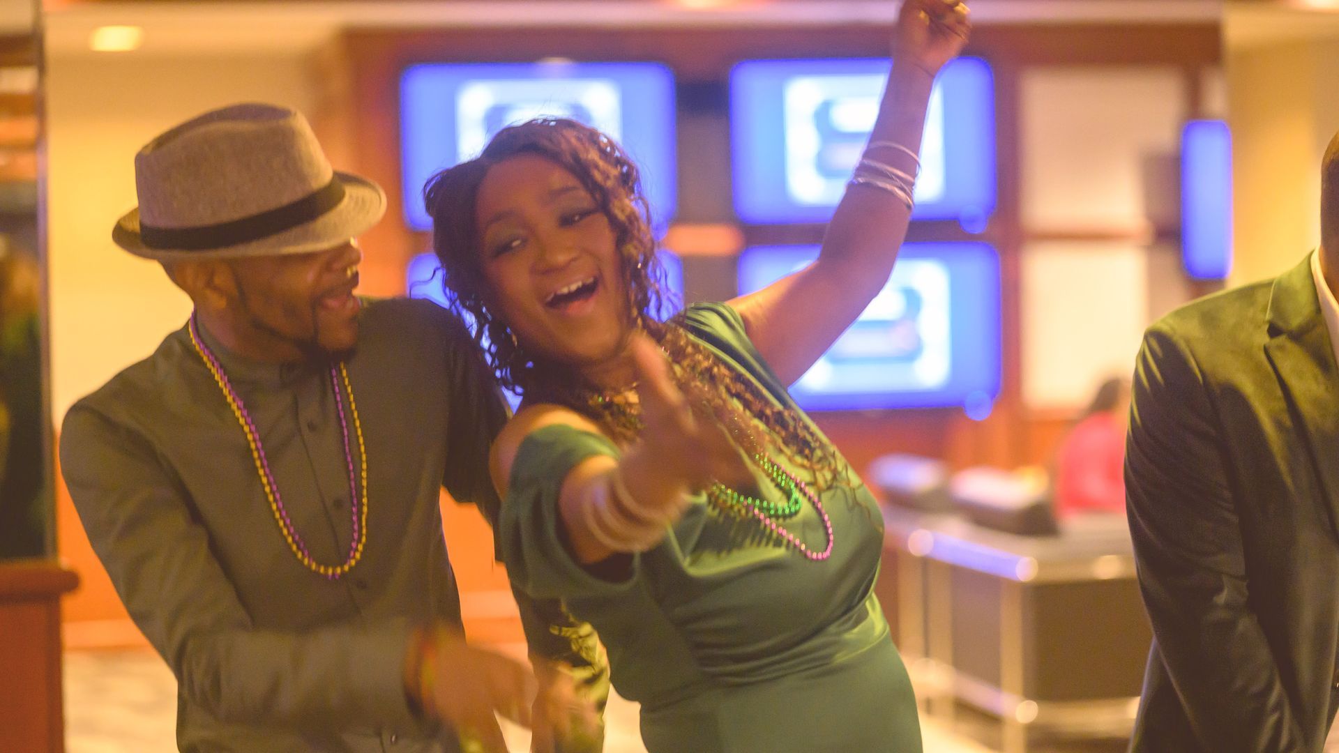 A woman in a green dress is dancing with a man in a hat.