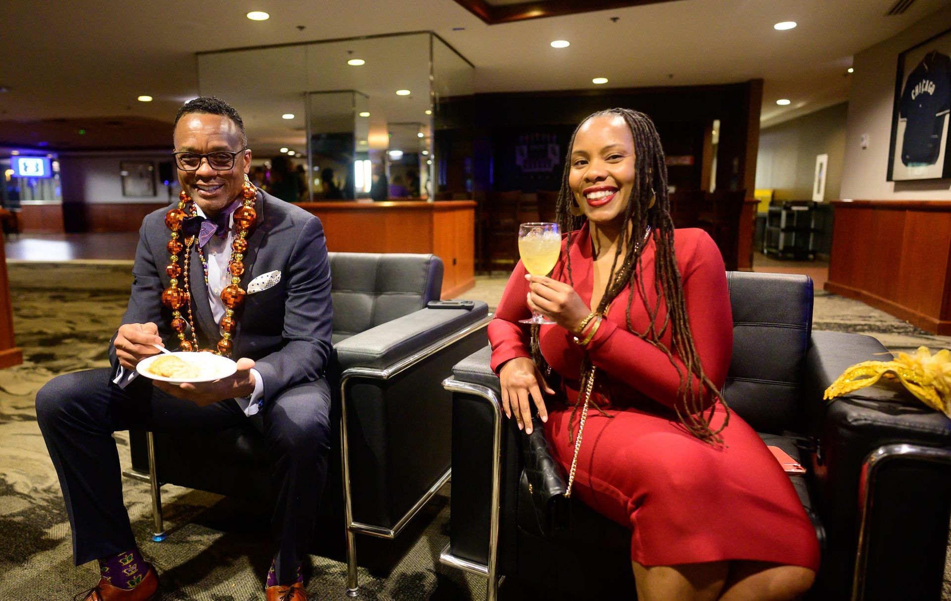 A man and a woman are sitting in chairs holding glasses of wine.