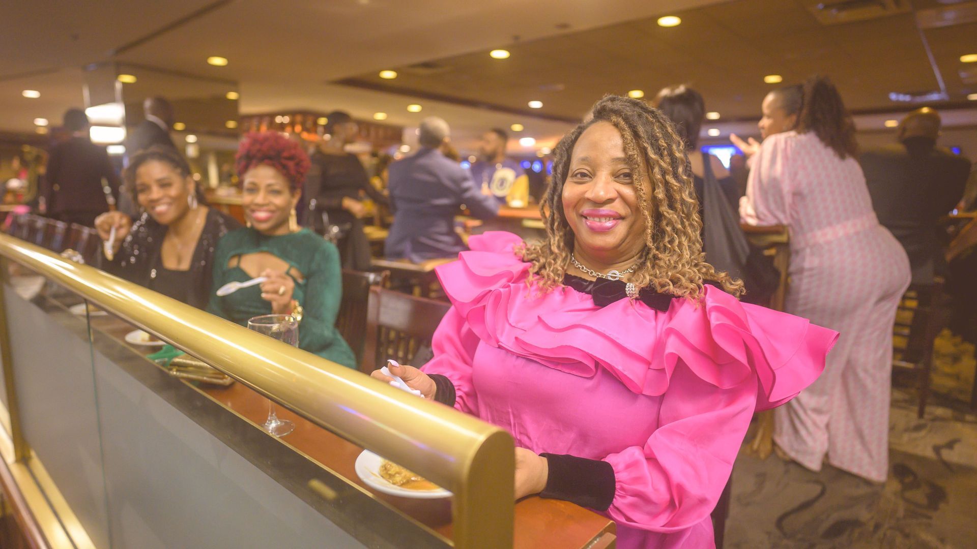 A woman in a pink dress is sitting at a table in a restaurant.
