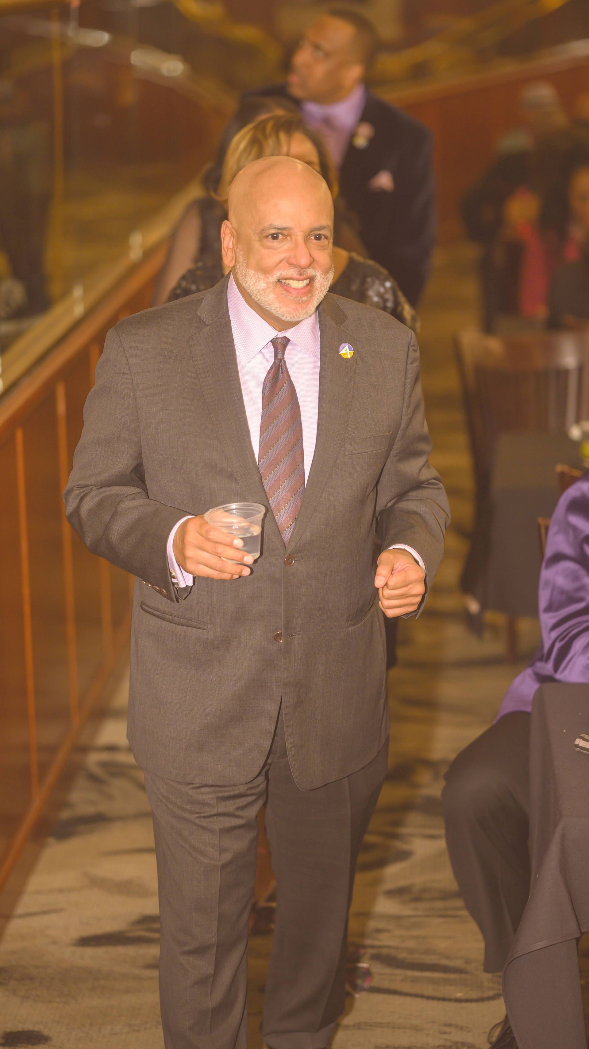 A man in a suit and tie is holding a glass of wine.