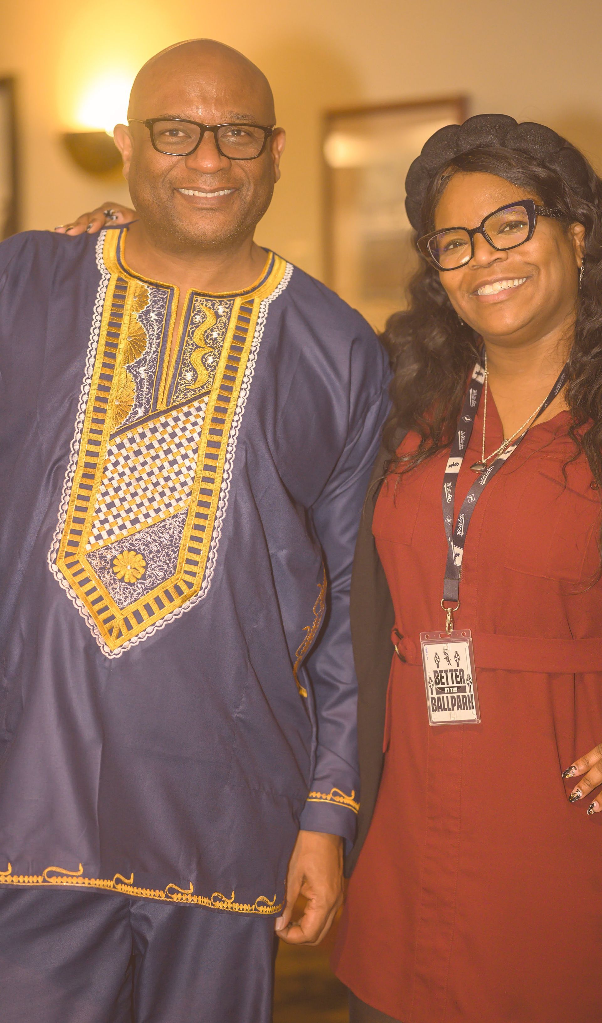 A man and a woman are posing for a picture together . the woman is wearing glasses and a lanyard.