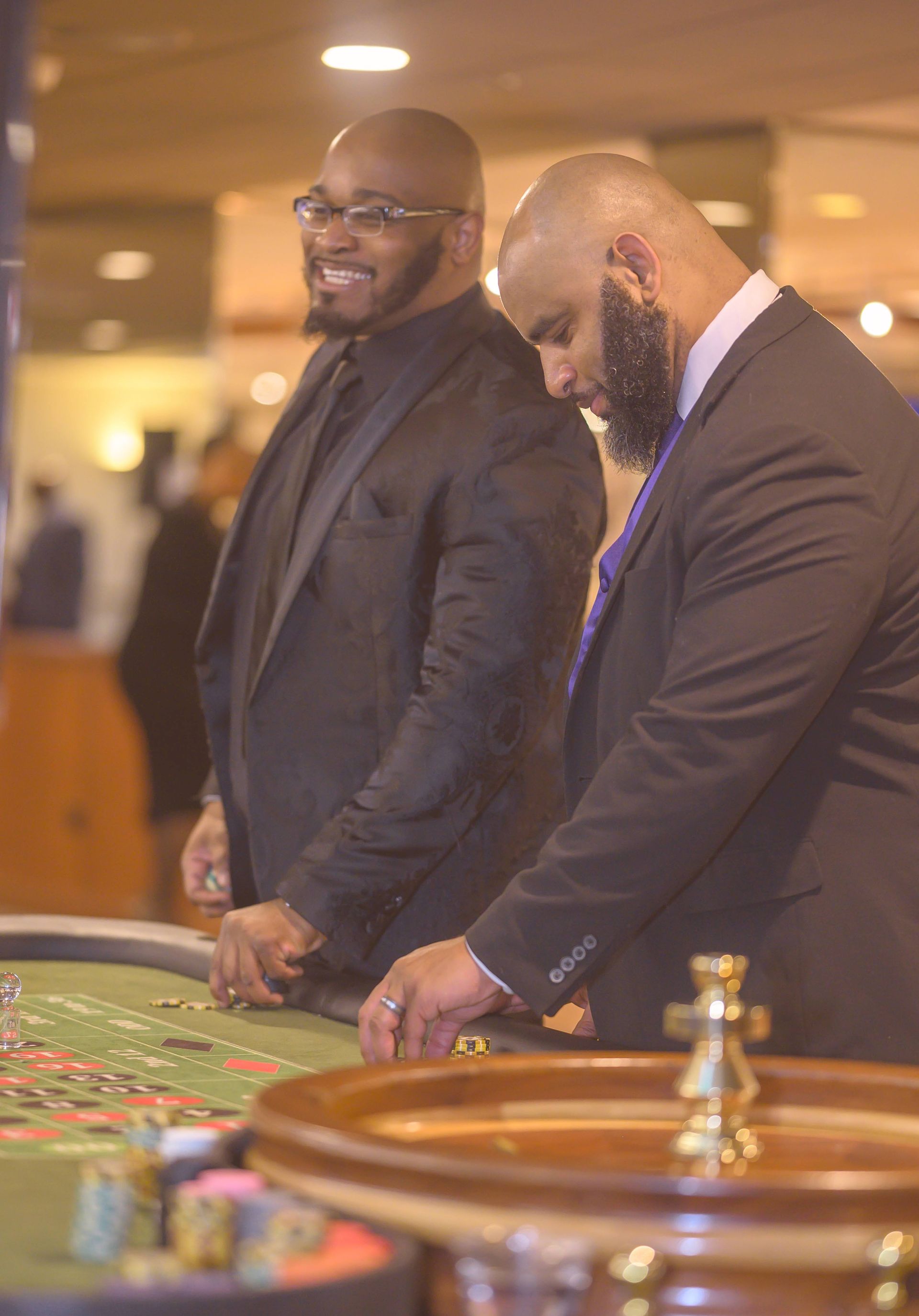 Two men in suits are playing roulette in a casino.