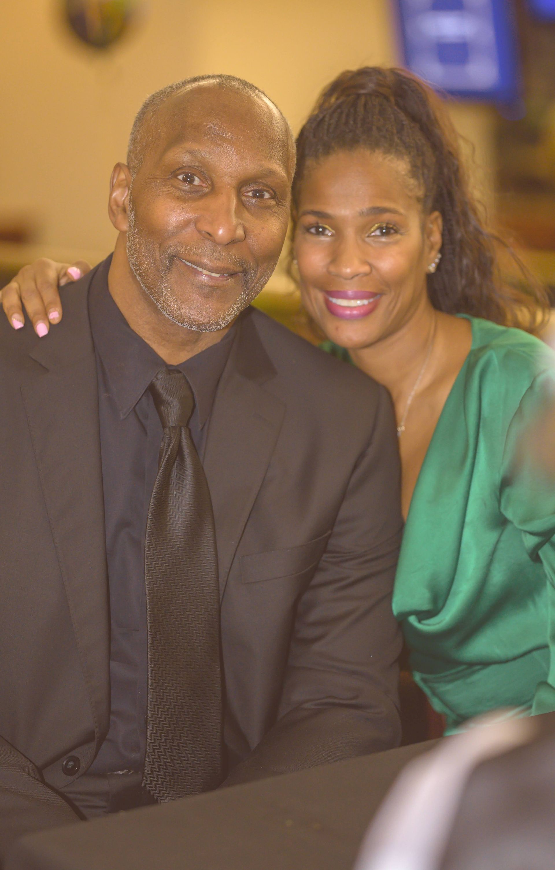 A man in a suit and tie is sitting next to a woman in a green dress.