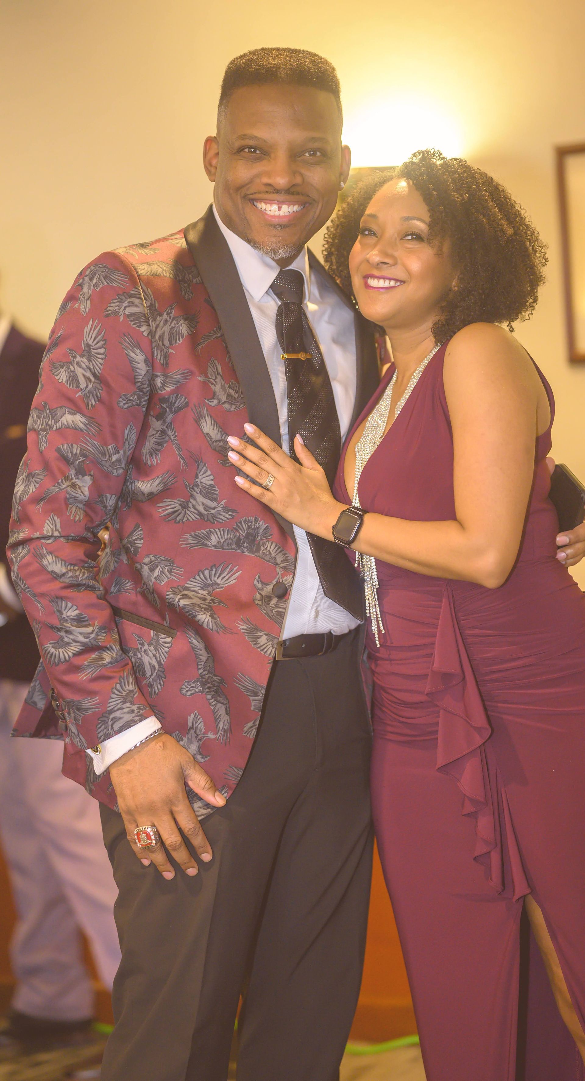 A man in a suit and tie is standing next to a woman in a burgundy dress.