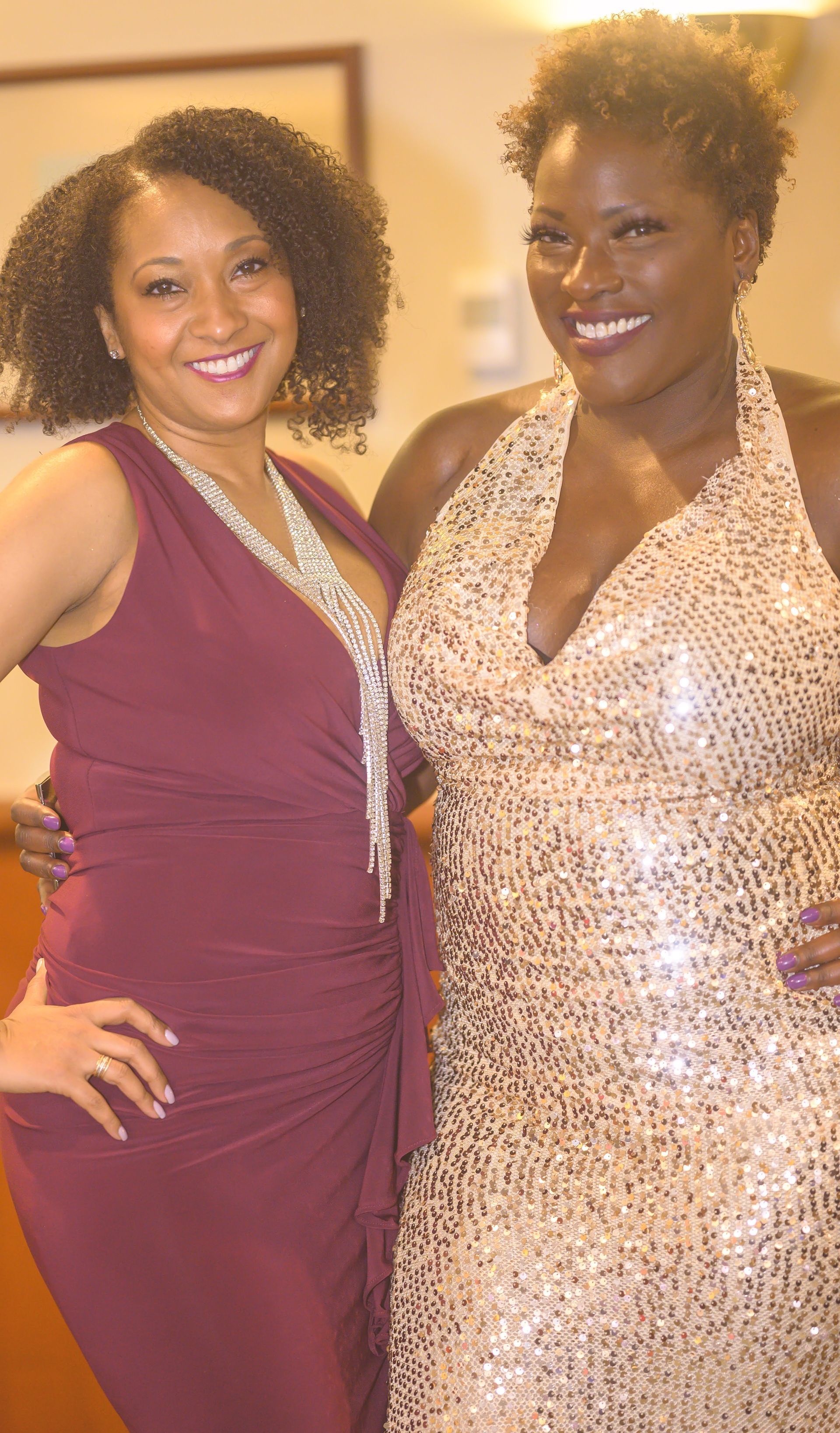 Two women in dresses are posing for a picture together.