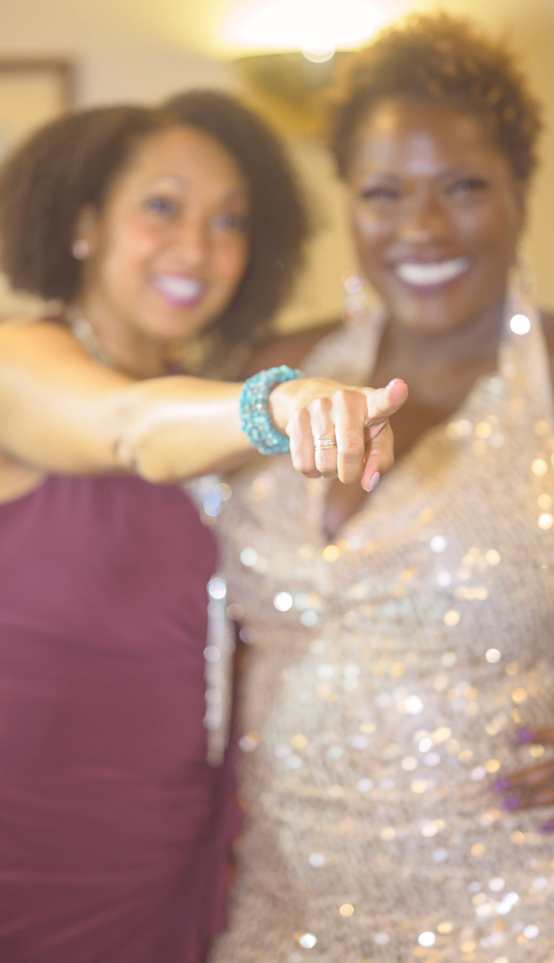 Two women are posing for a picture and one is pointing at the camera.