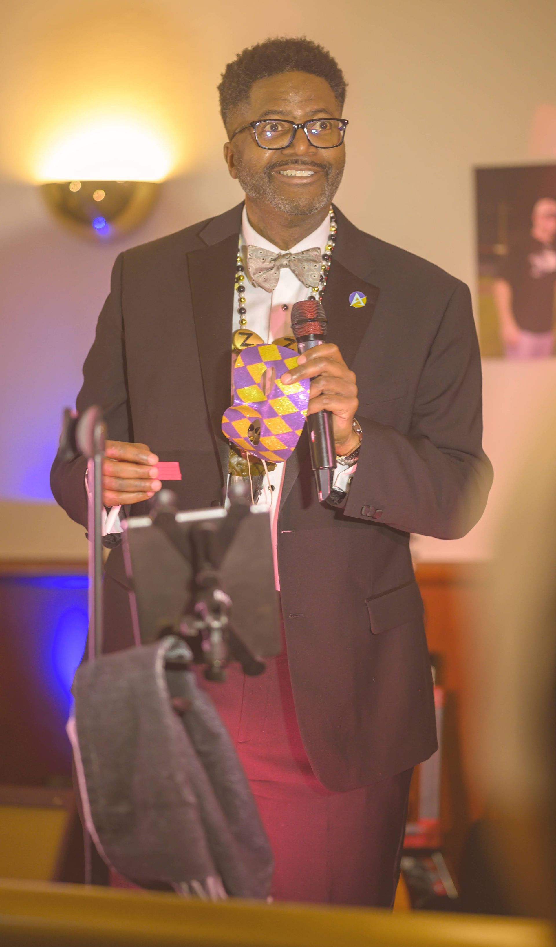 A man in a suit and bow tie is holding a microphone.
