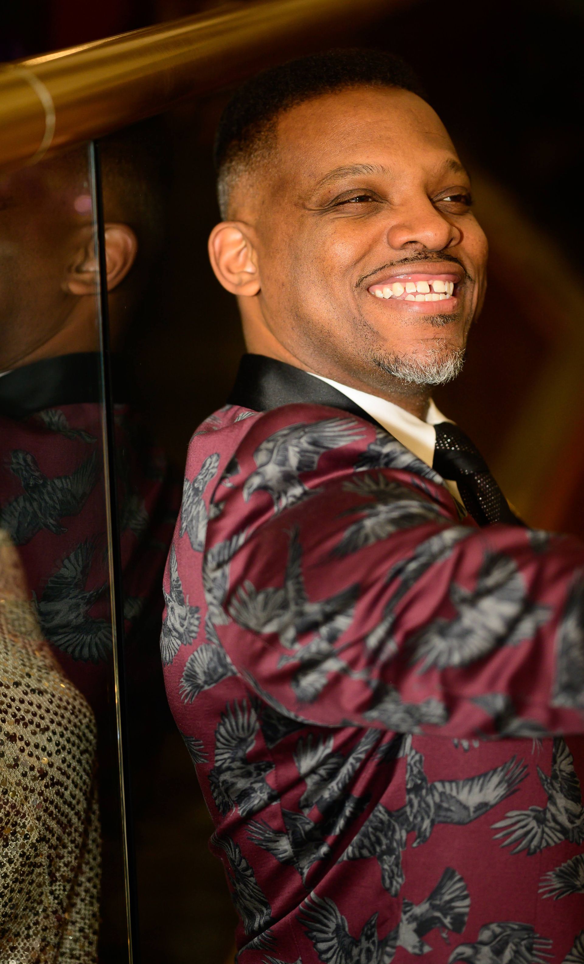 A man in a suit and tie is smiling in front of a mirror.