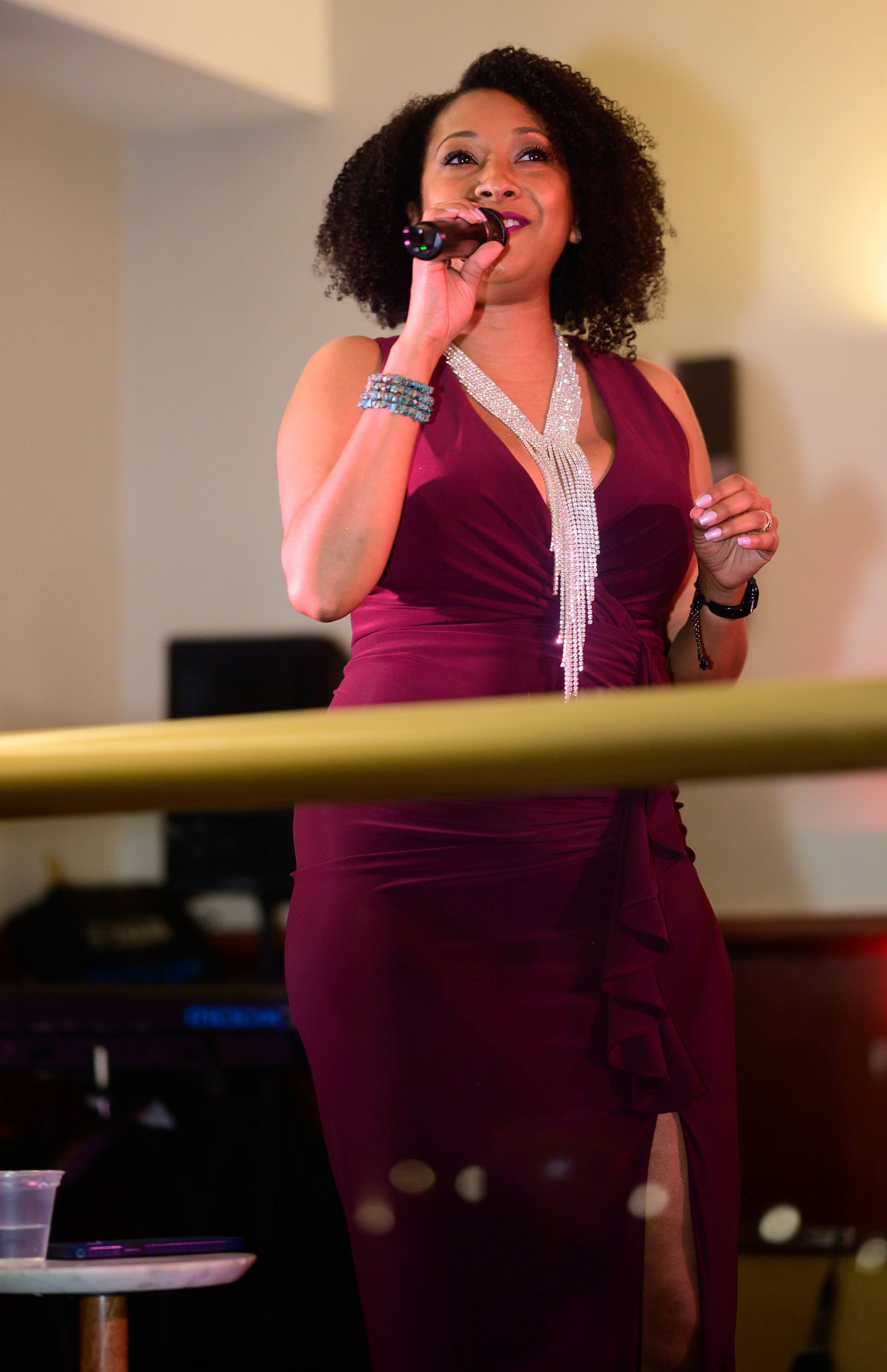 A woman in a purple dress is singing into a microphone.
