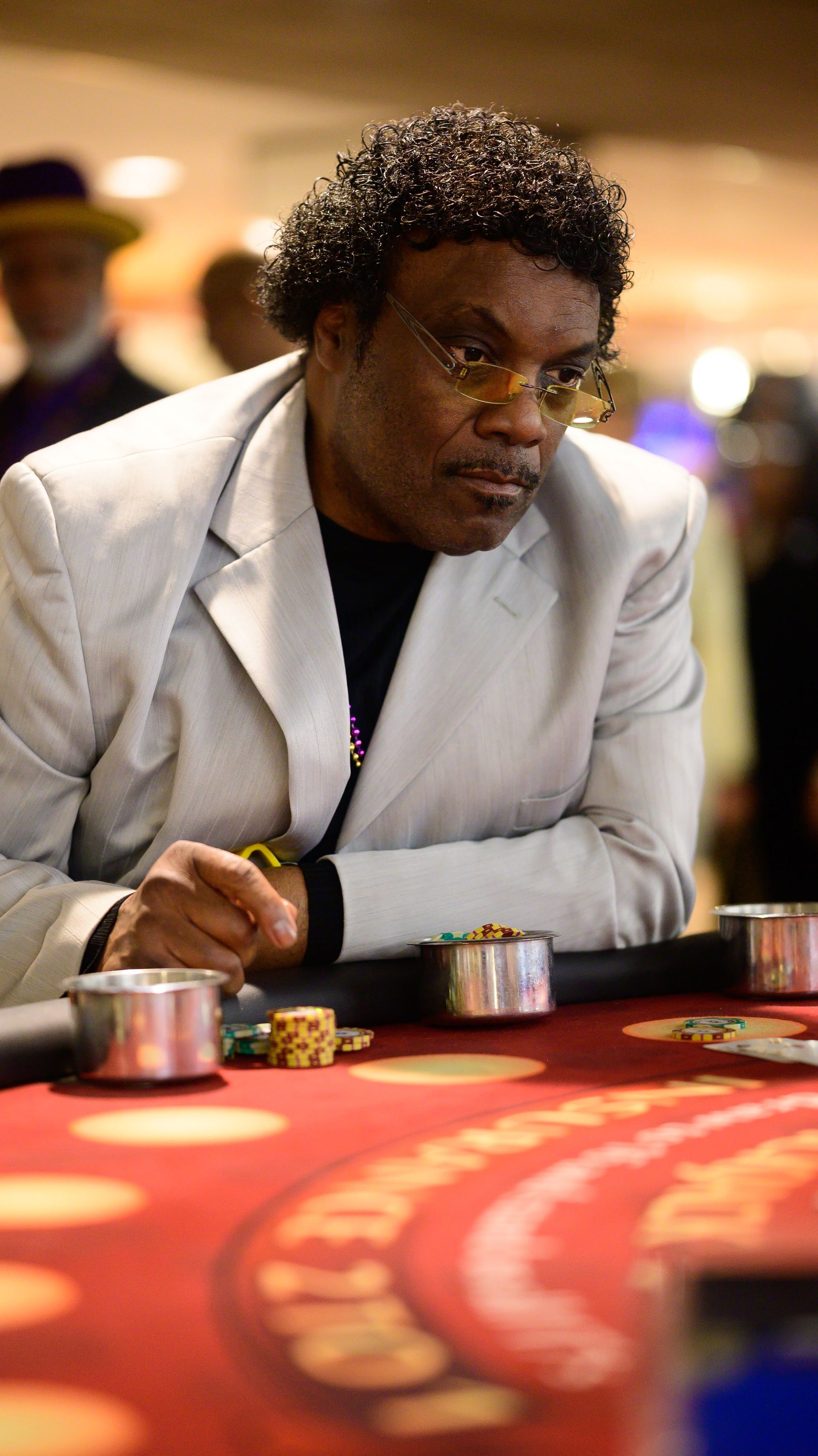 A man is sitting at a table in a casino playing poker.