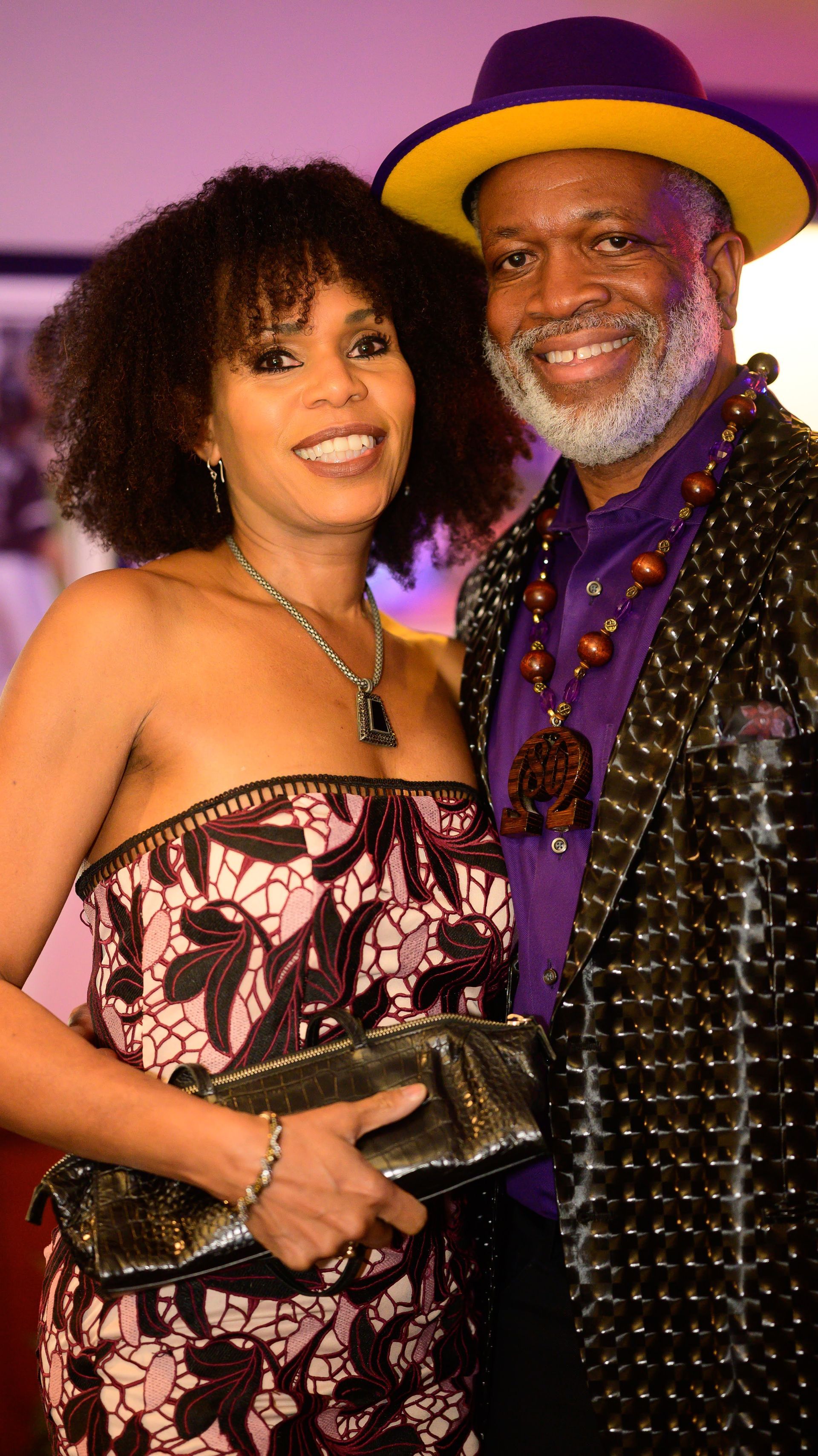 A man and a woman are posing for a picture together . the man is wearing a yellow hat.