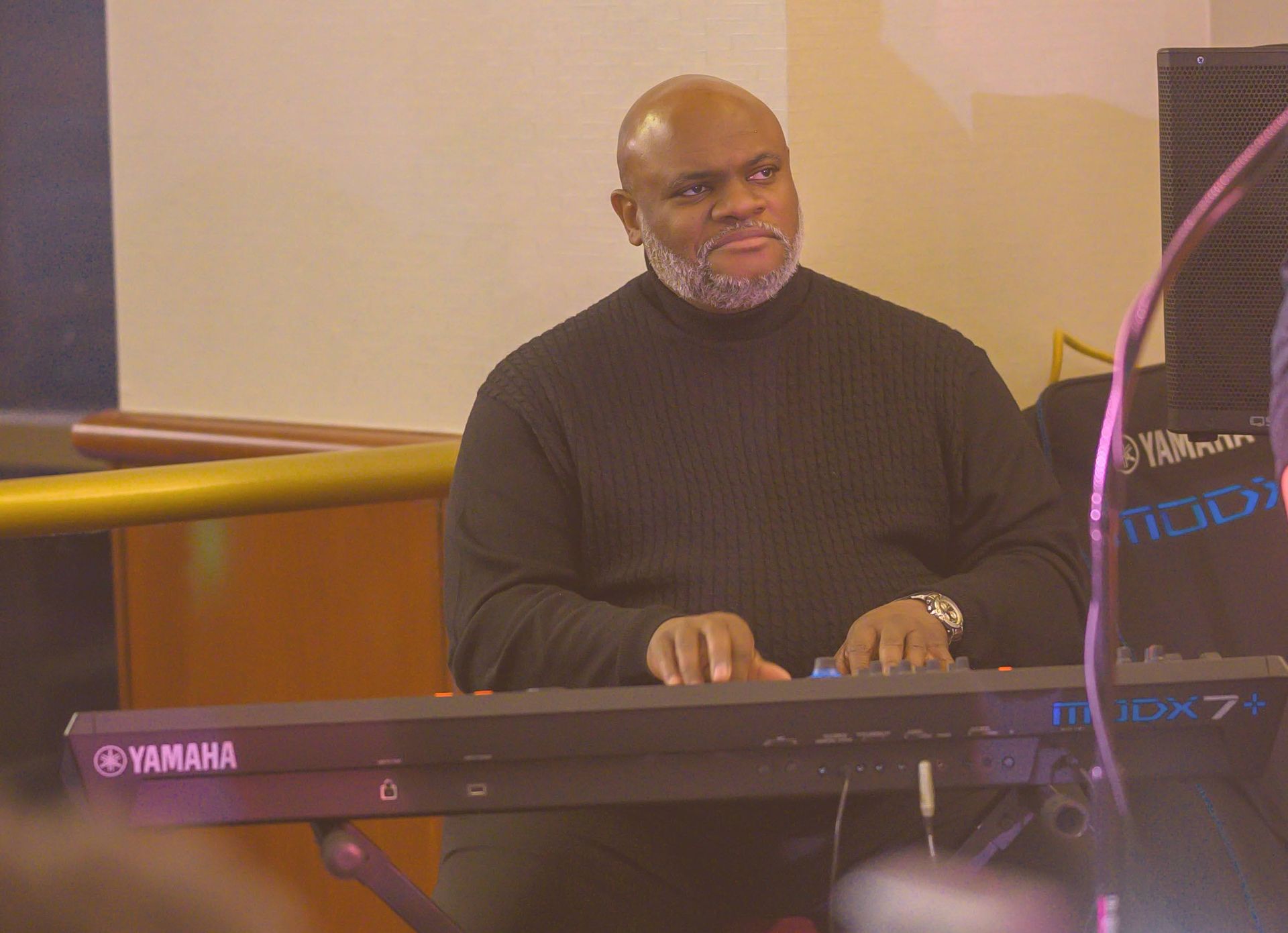A man is playing a yamaha keyboard in a room.