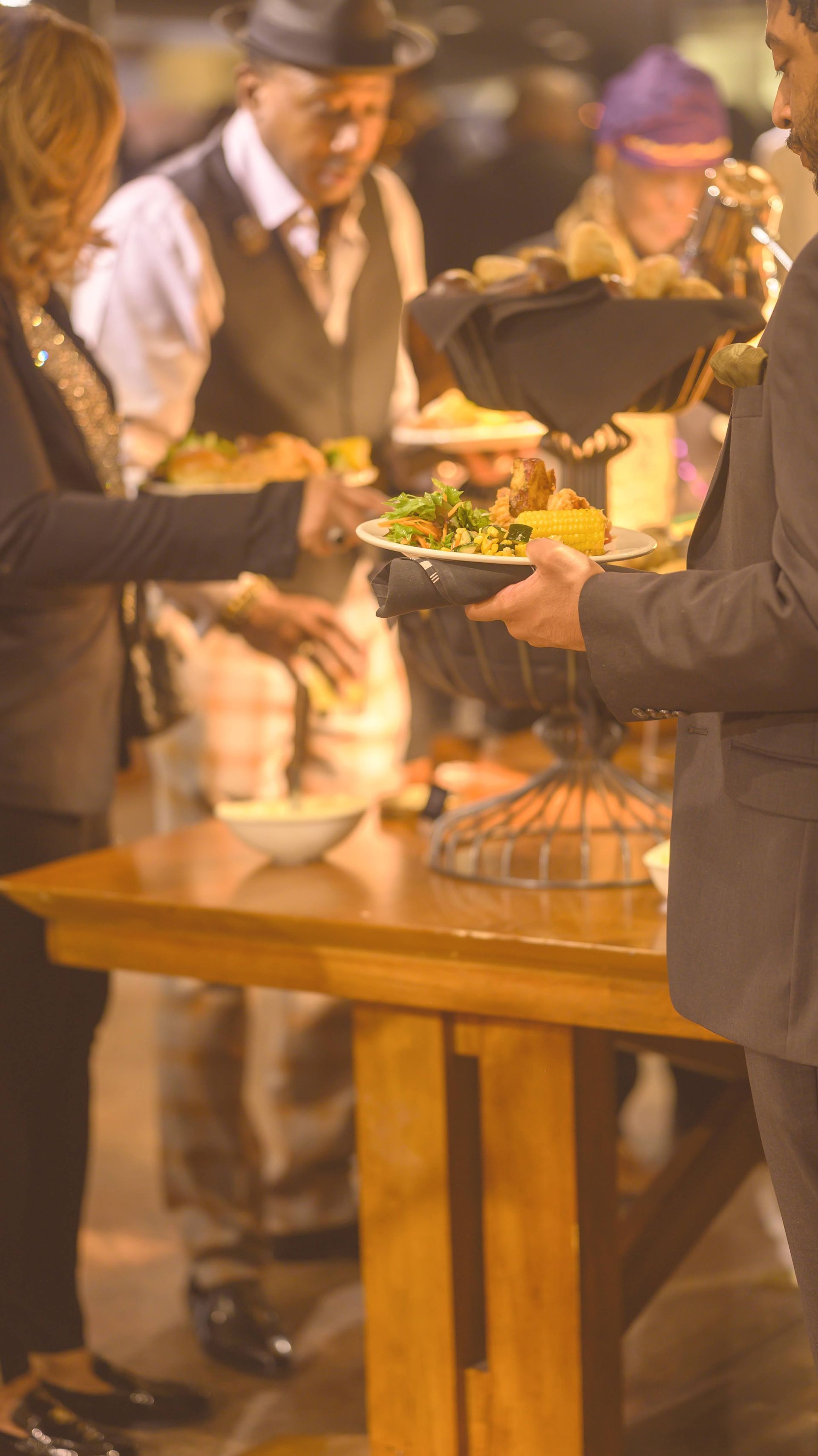 A group of people are standing around a table eating food.