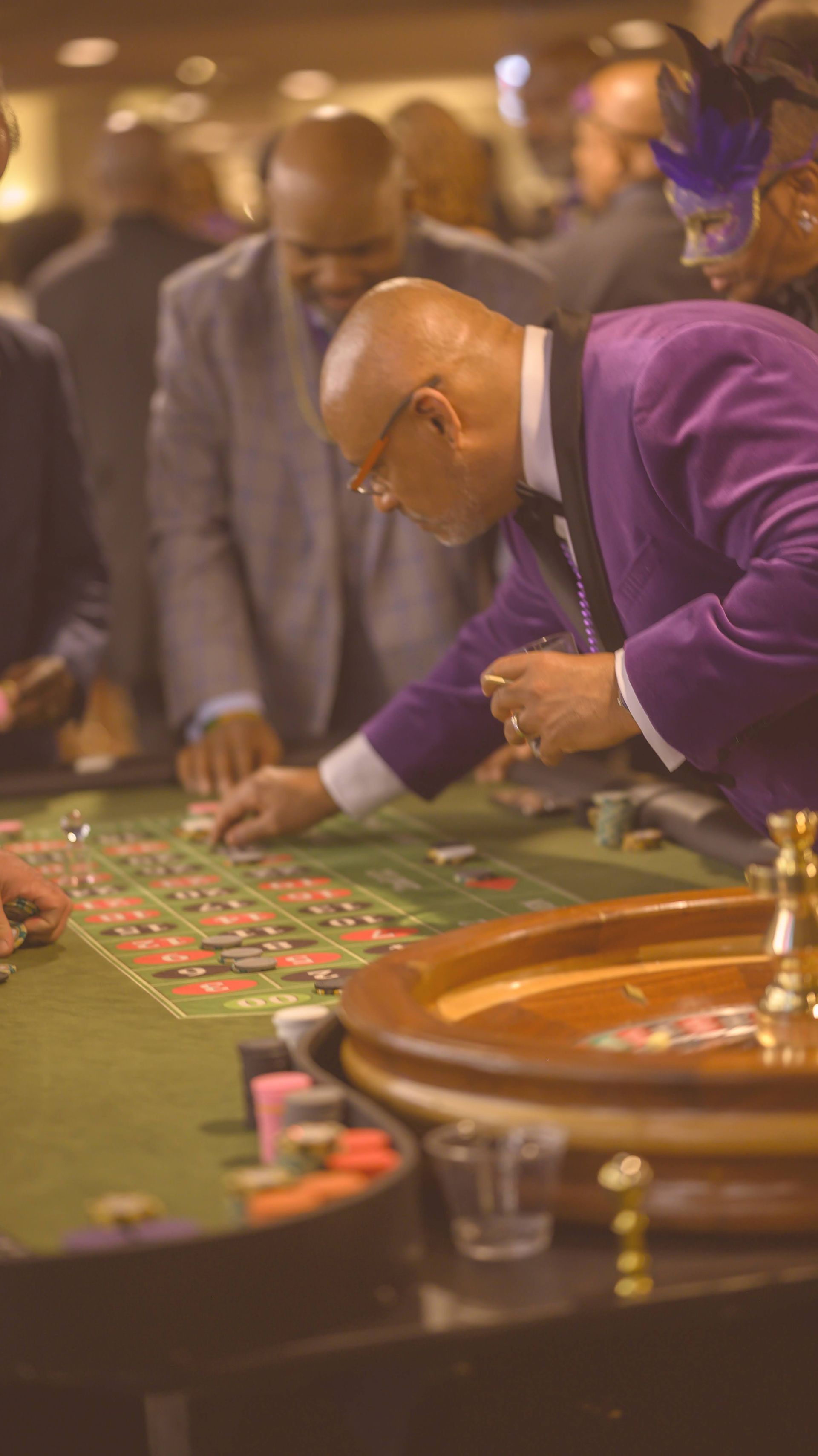 A man in a purple suit is playing roulette in a casino.