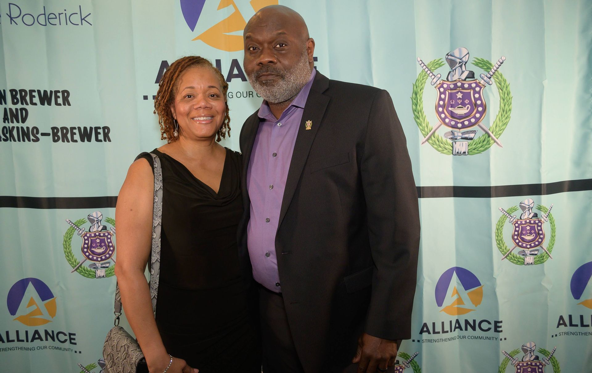 A man and a woman are posing for a picture in front of a banner that says alliance