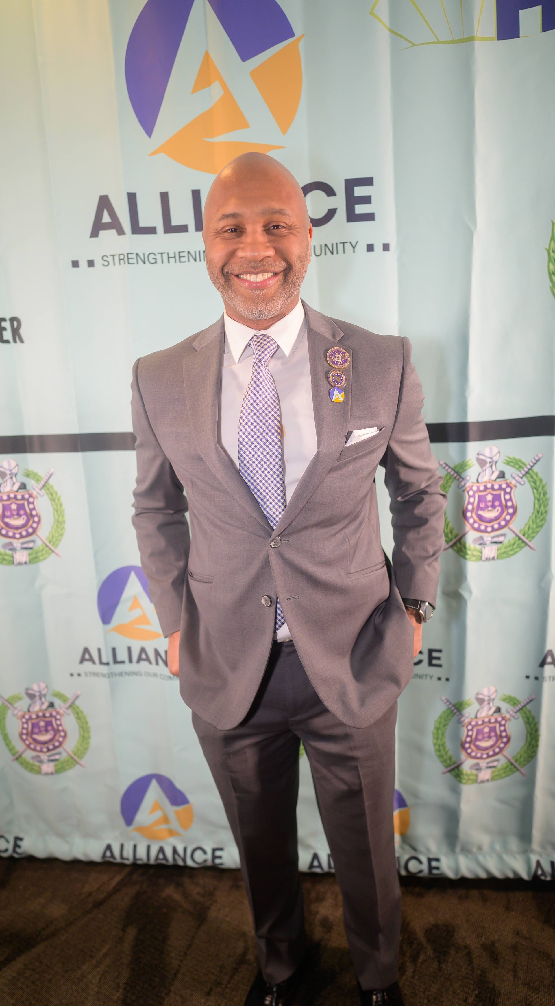 A man in a suit and tie is standing in front of a wall.