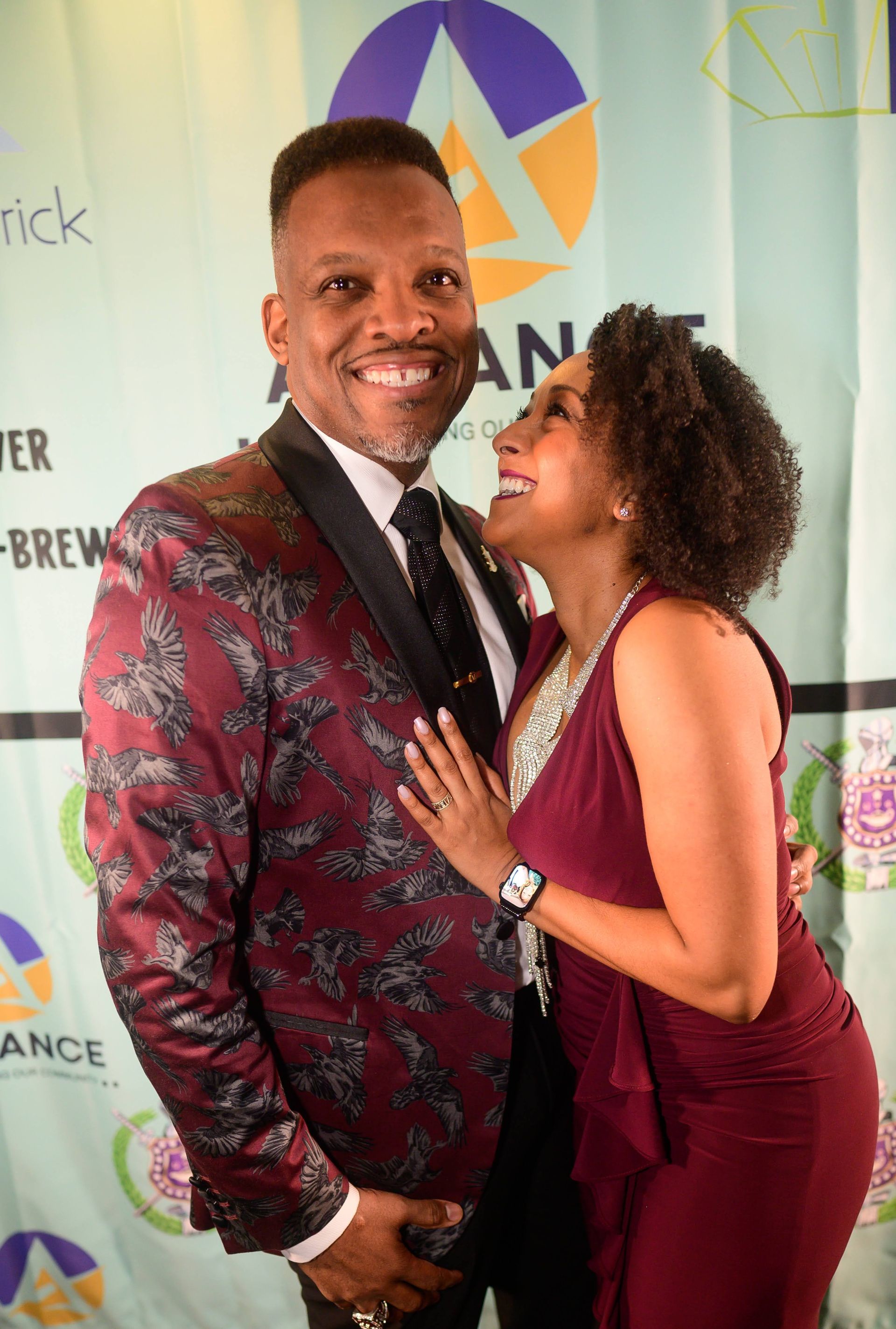 A man in a suit and tie is standing next to a woman in a red dress.