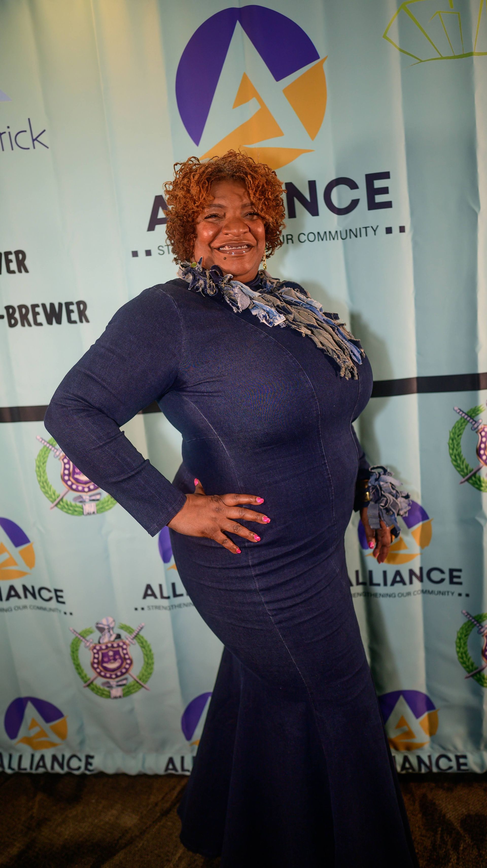 A woman in a purple dress is standing in front of a backdrop.