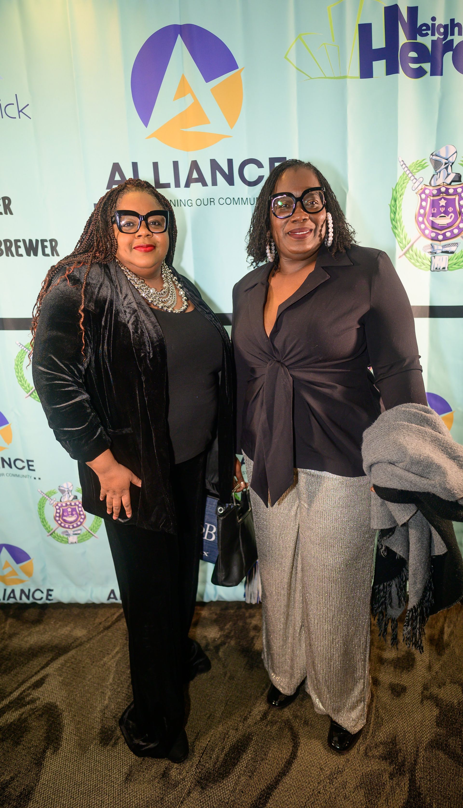 Two women are standing next to each other in front of a banner.
