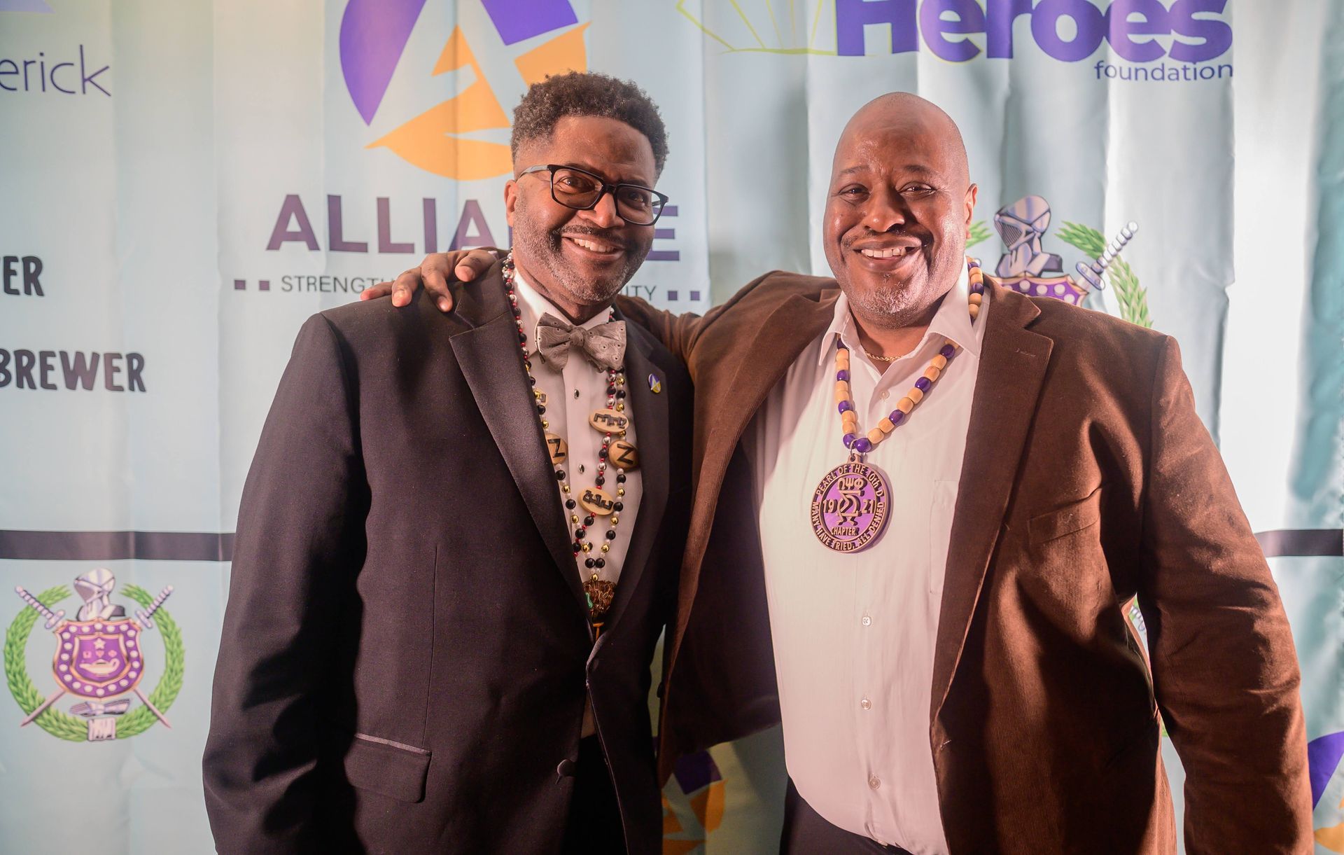Two men in suits and bow ties are posing for a picture.