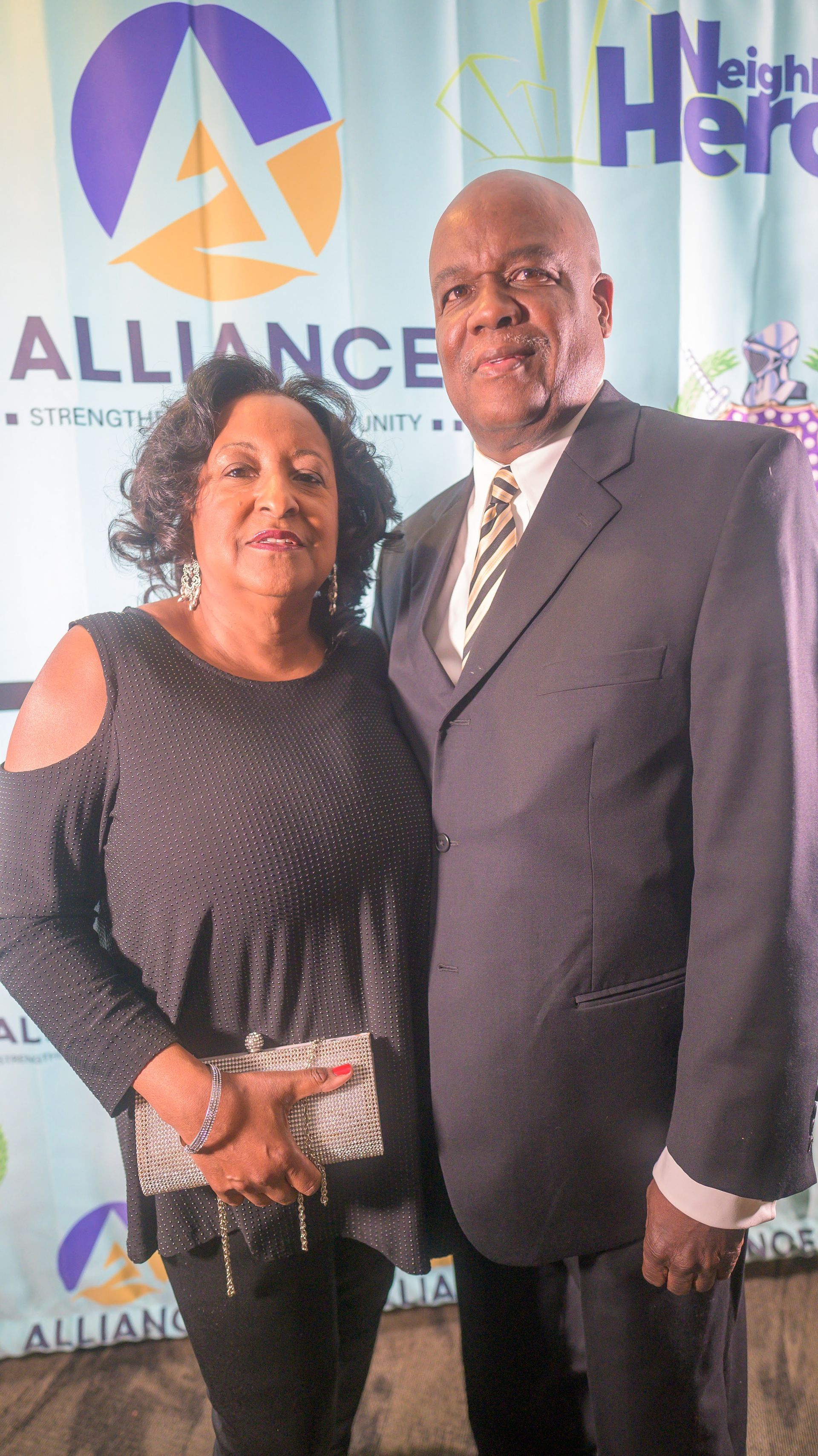 A man and a woman are posing for a picture in front of a banner.
